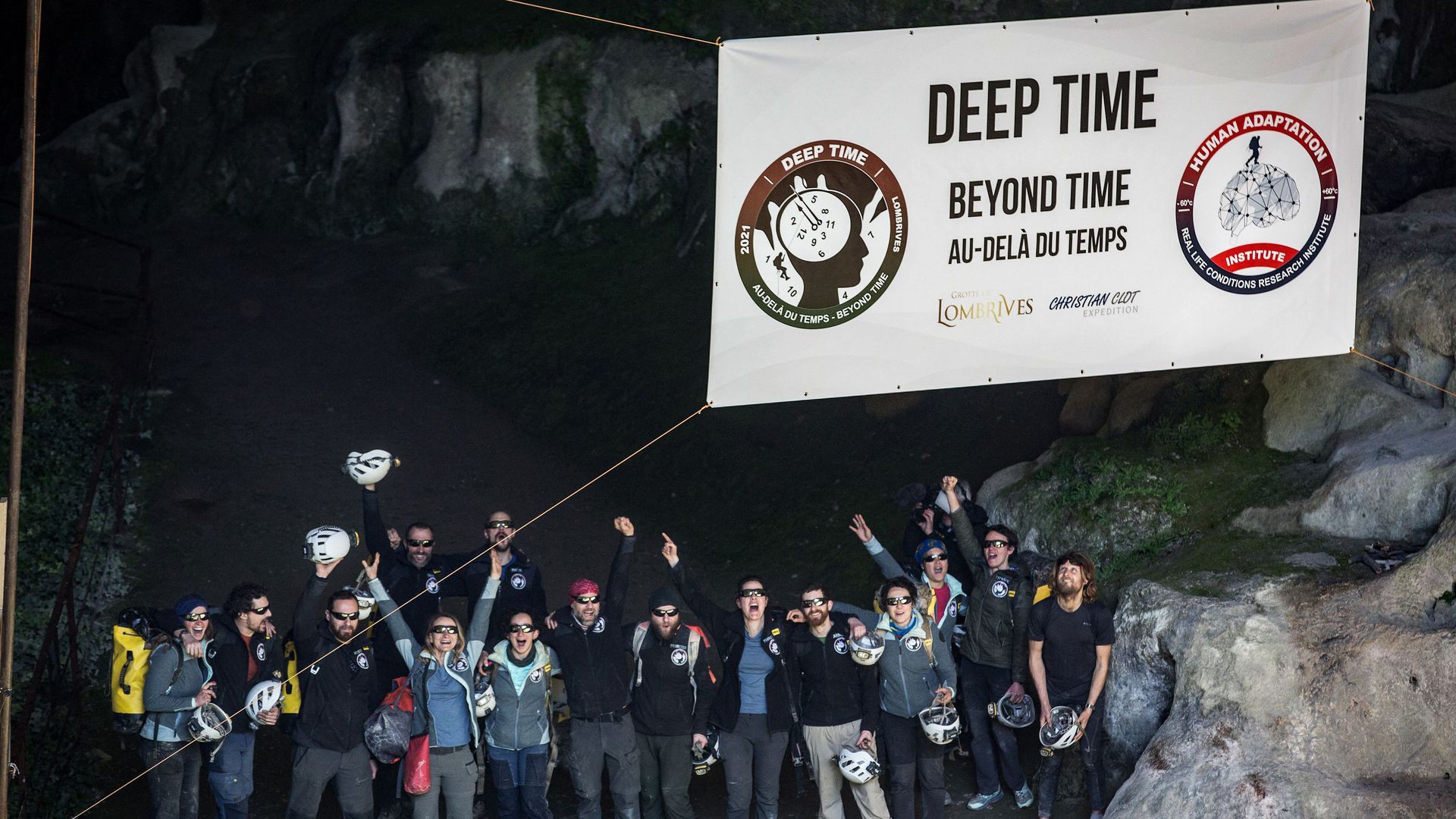 Photo of a group of people cheering at the mouth of a cave