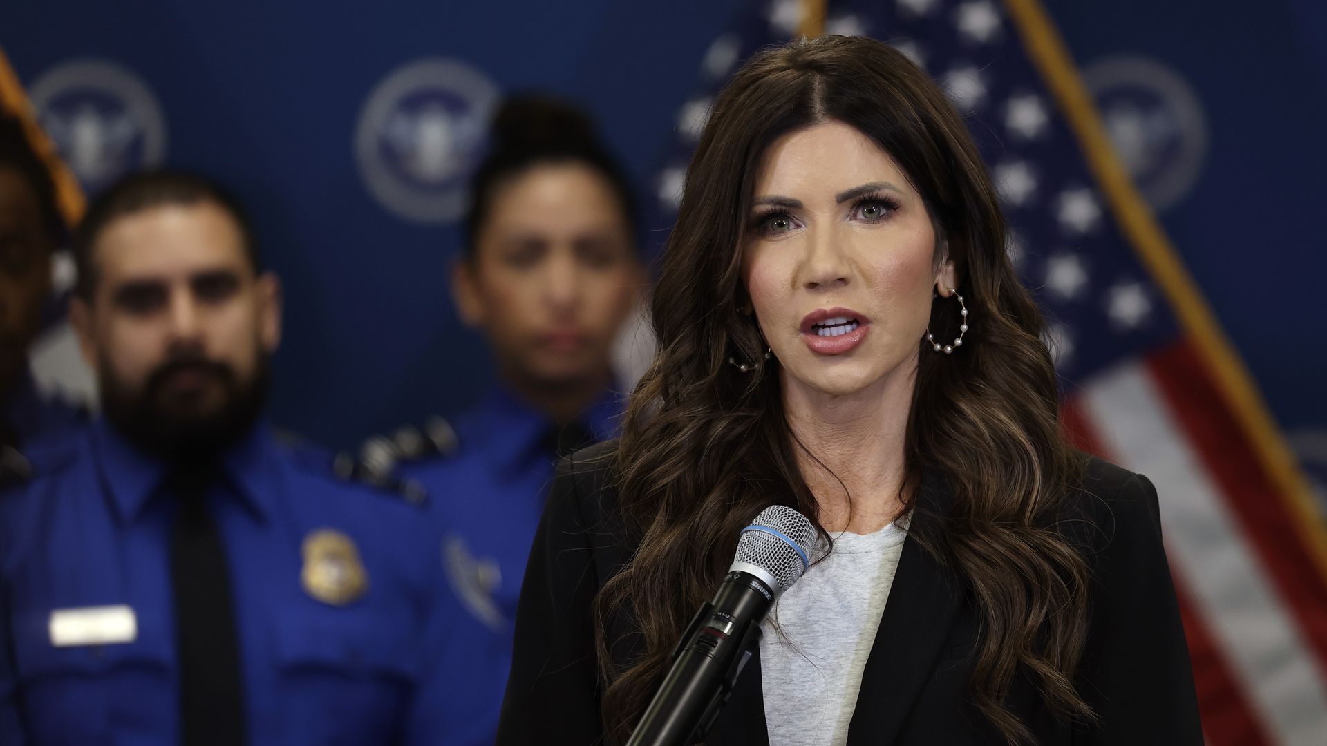 Kristi Noem, the U.S. secretary of homeland security, speaks at a podium during a press conference at Miami International Airport.