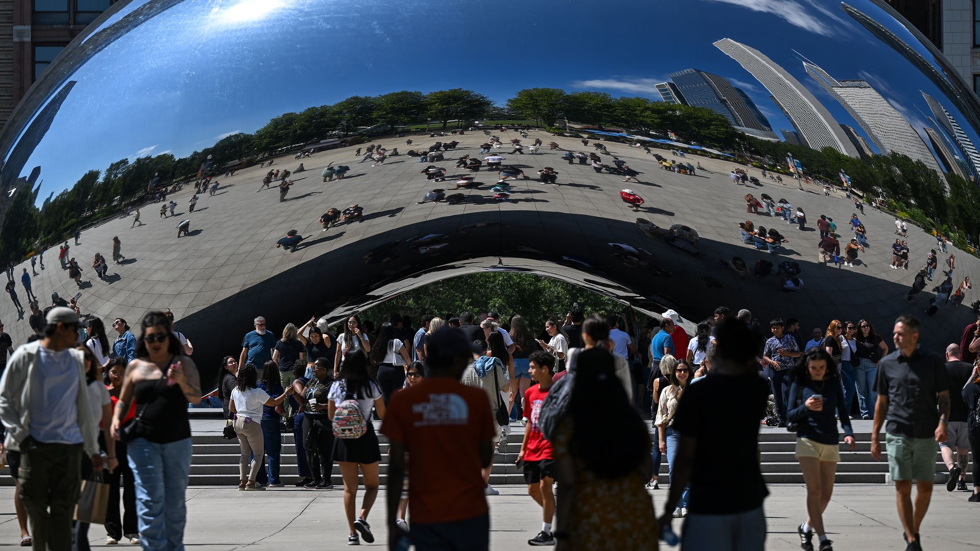 "The Bean" sculpture in Chicago reflecting people who are standing in front of it.