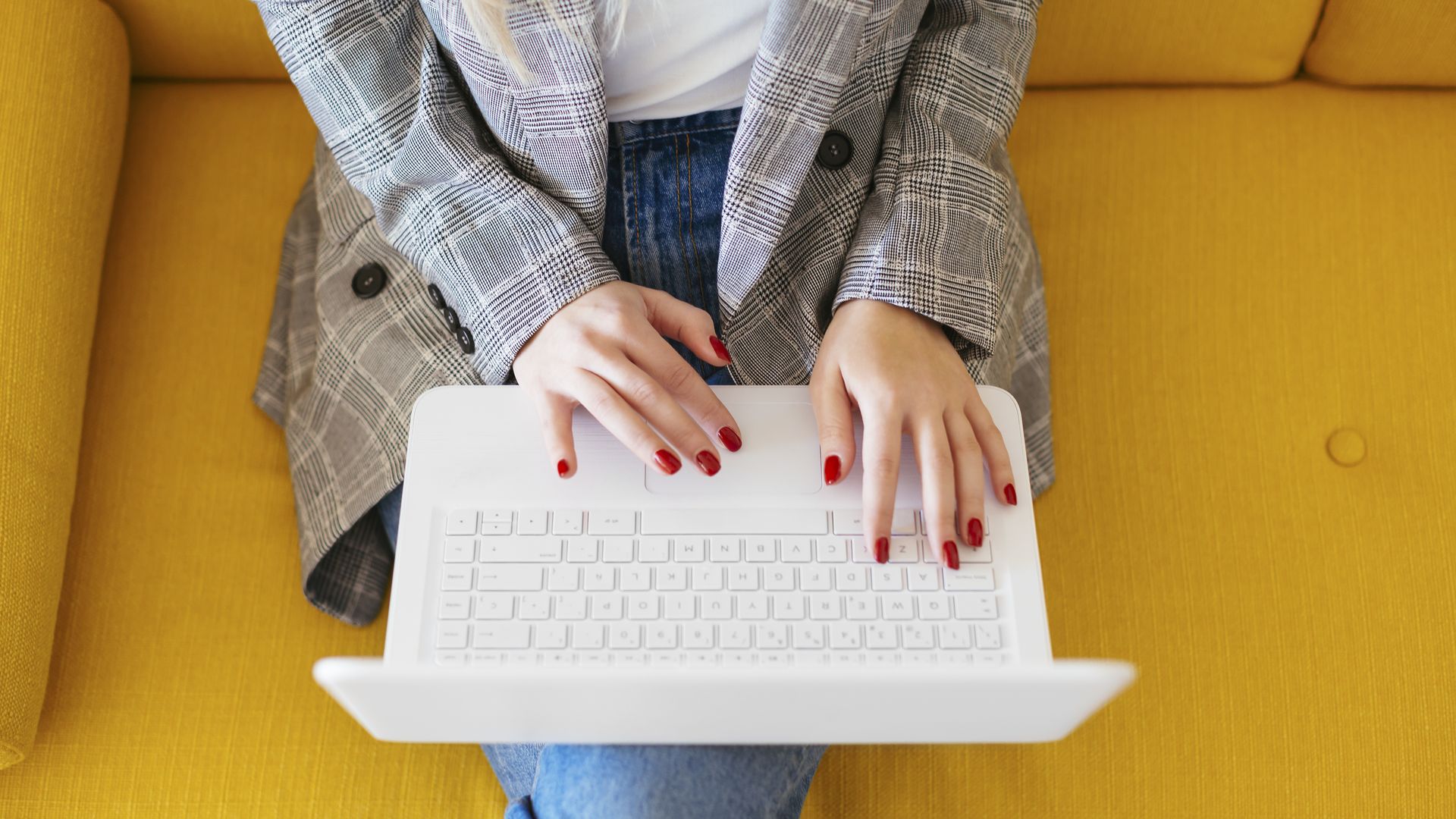 A woman working on a couch, with a laptop