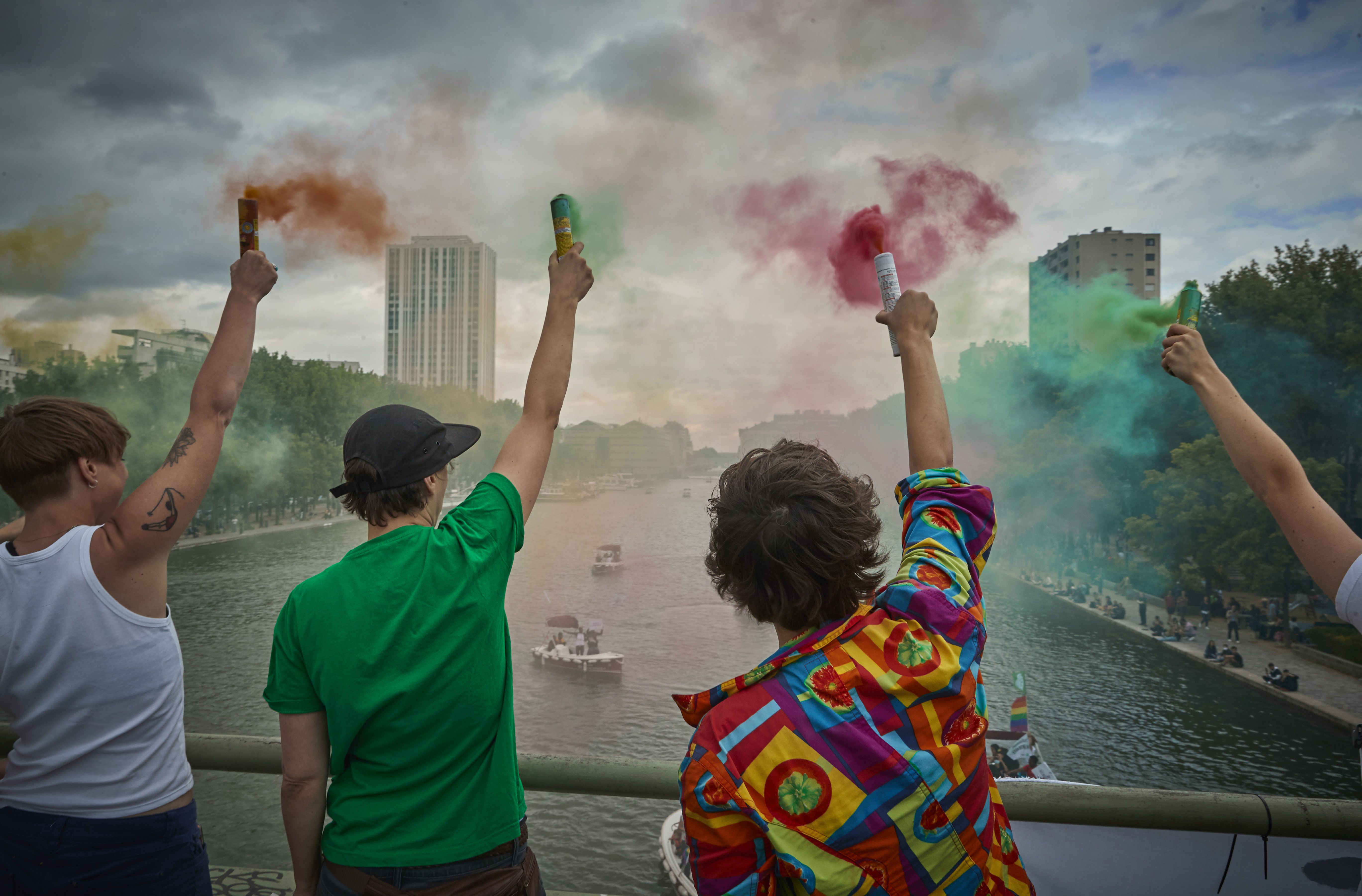 Revellers hold flayers in the colours of the Rainbow Flag to celebrate unofficial Gay Pride on the banks and in the water of the Canal de l'Ourcq on June 27, 2020 in Paris, France. 