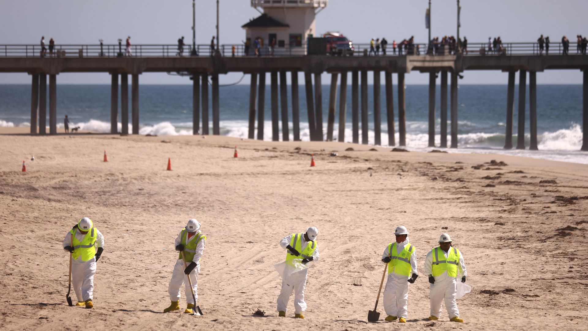  Oil spill cleanup workers search for contaminated sand and seaweed on a mostly empty Huntington Beach in California on Oct. 9. 