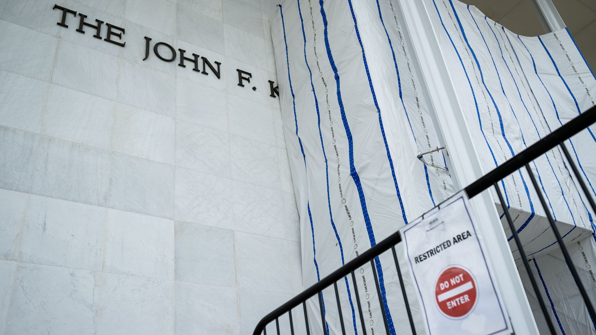 Fencing around a tarp covering the facade of the Kennedy Center.
