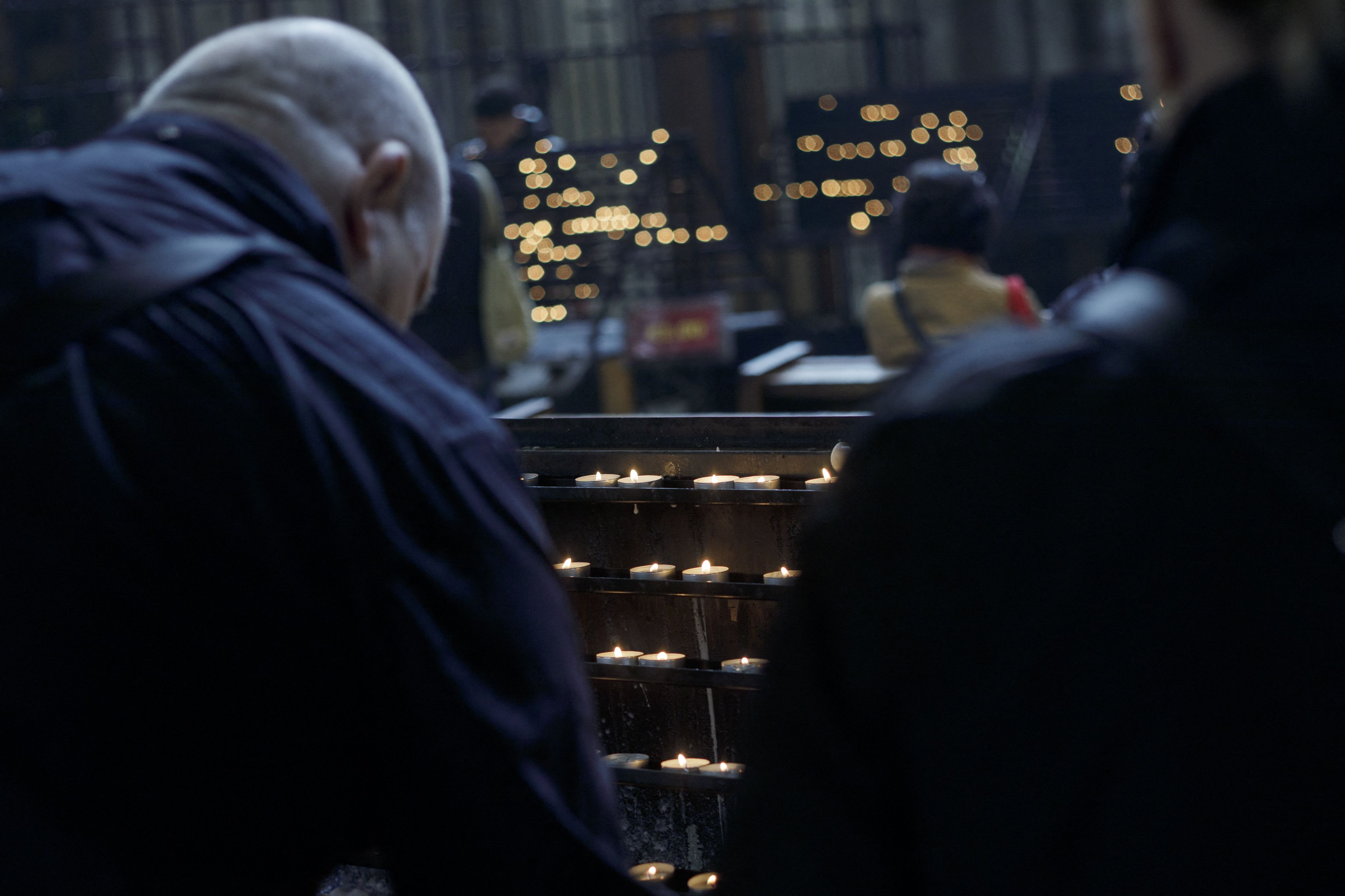 People in a church light candles