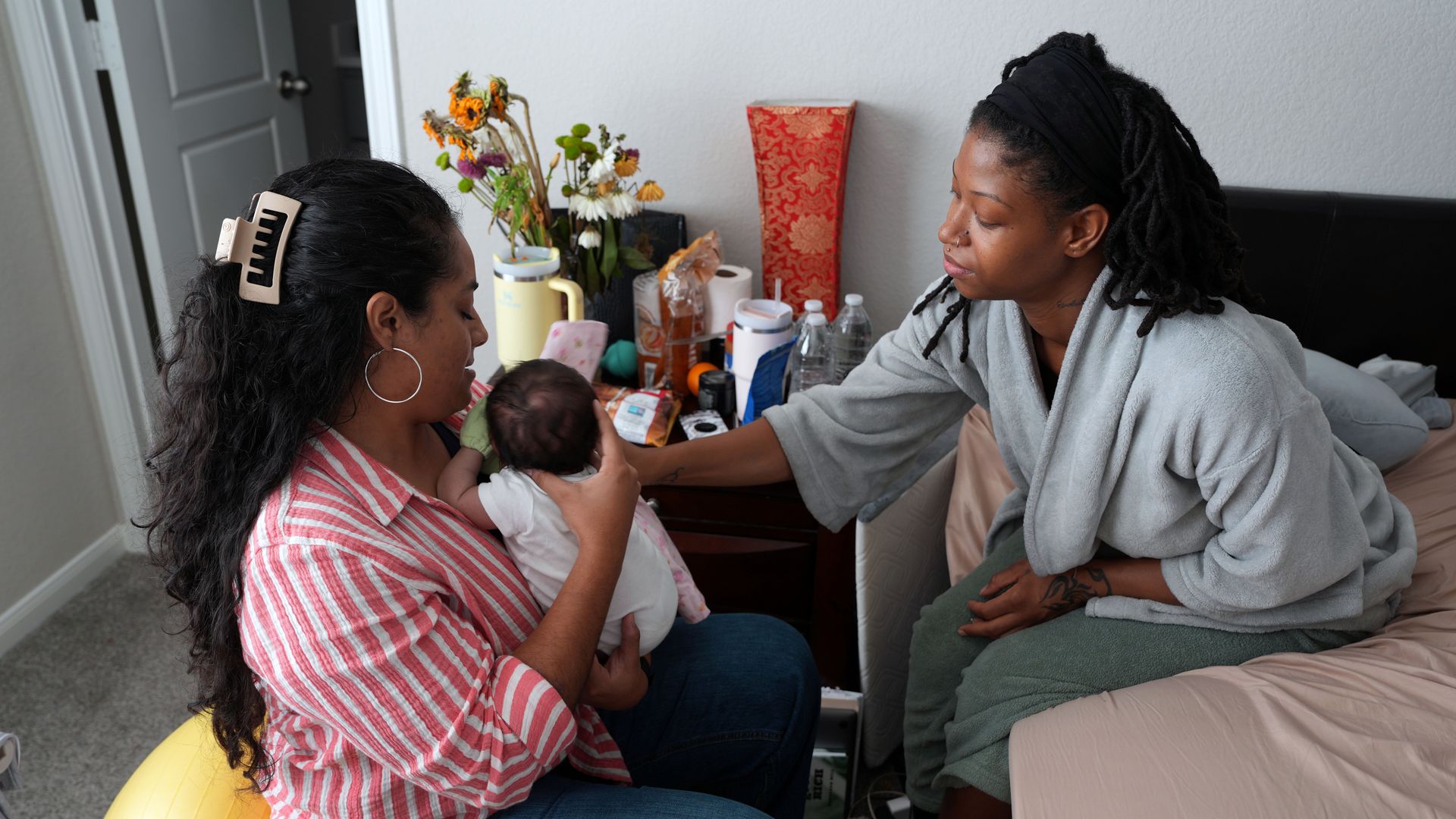 Melina Laverde, left, performs cranial sacral therapy on Sanaai Lynae, two weeks old, during a postpartum checkup on Destyni McClain in Houston, Friday, July 25, 2025. 
