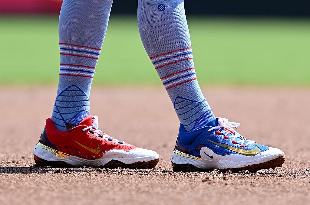 A photo showing two feet wearing high red, white and blue striped and starred socks. One shoe is red and the other is blue.