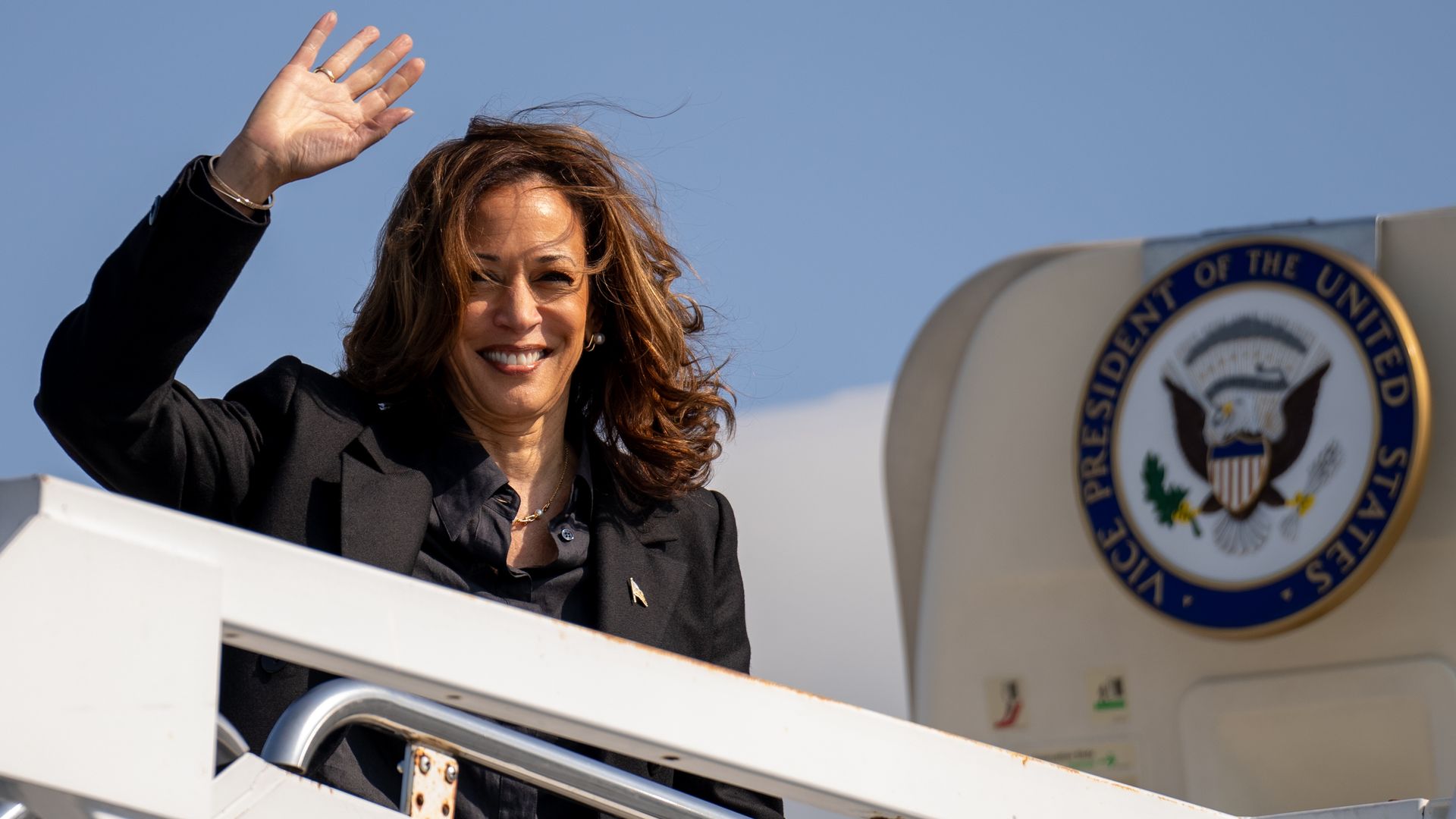 Vice President Kamal Harris waves as she boards her plane.