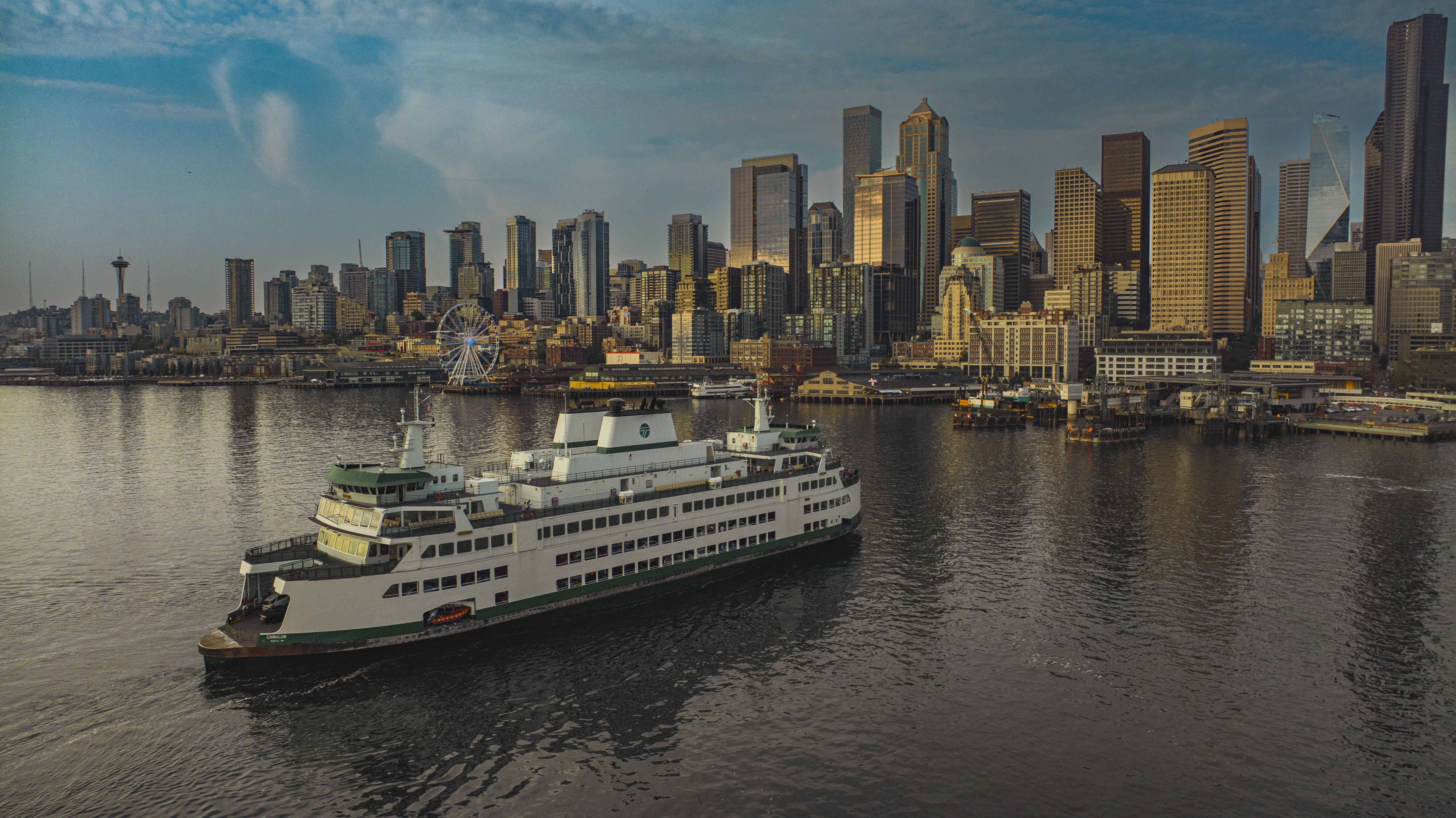 A ferry plies the waters near the dock in downtown Seattle with the city skyline in the background.