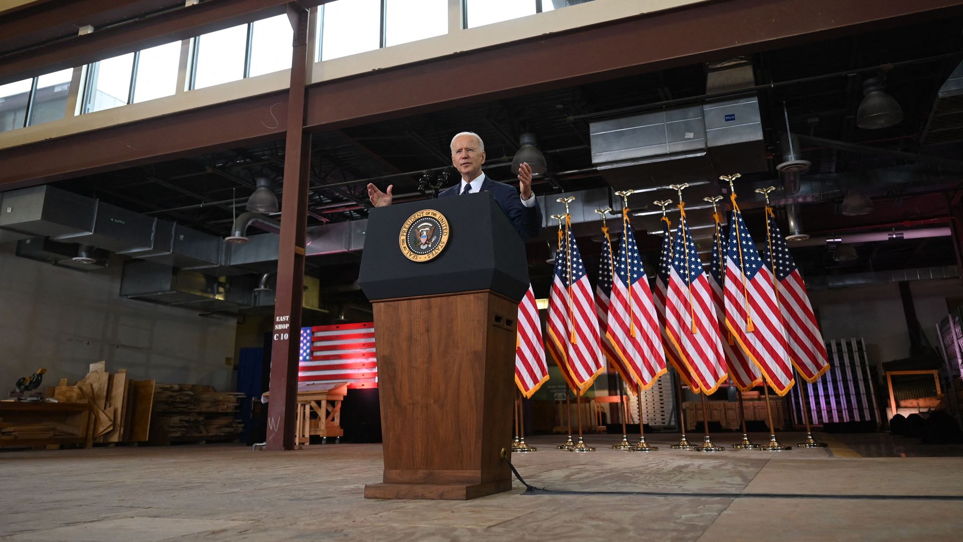 Biden speaks in front of flags.