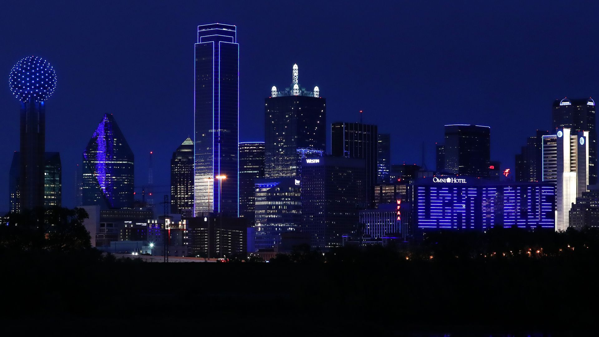 A photo of the Dallas skyline lit blue