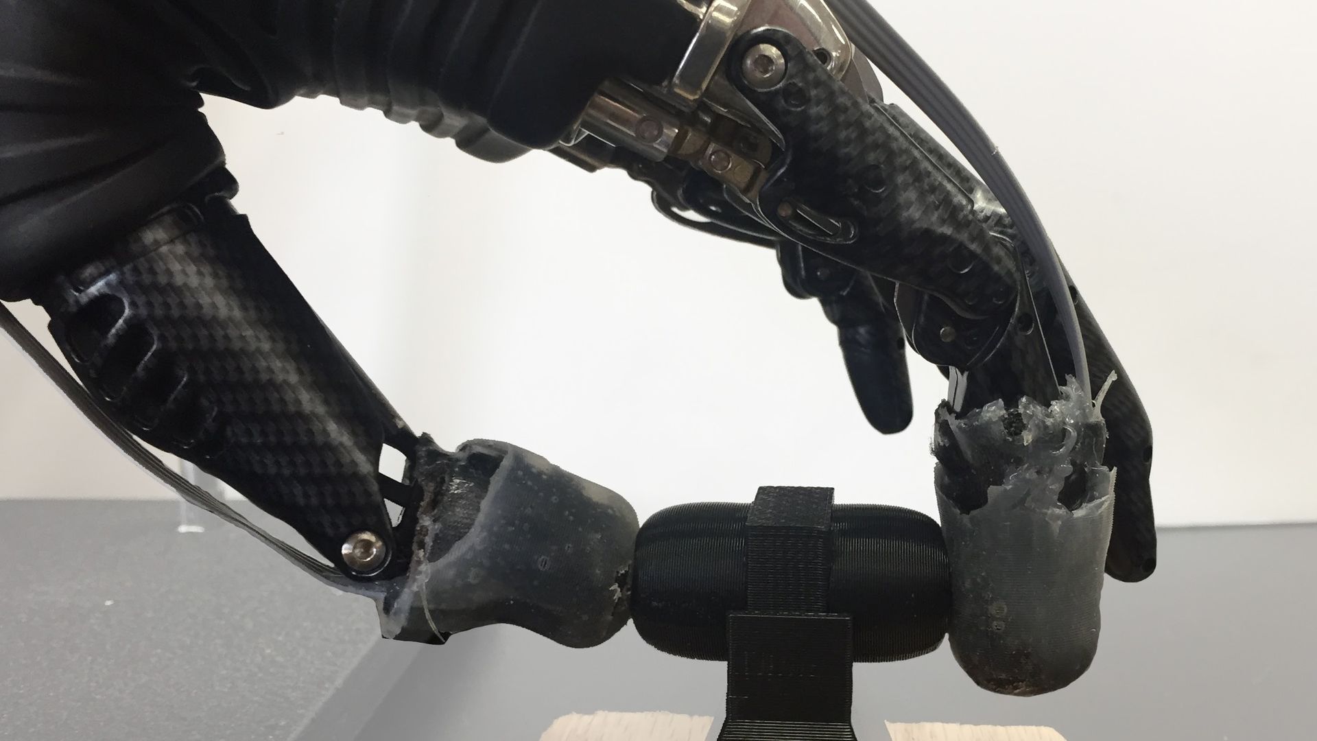 A prosthesis with e-dermis on its fingertips picks up an object. 