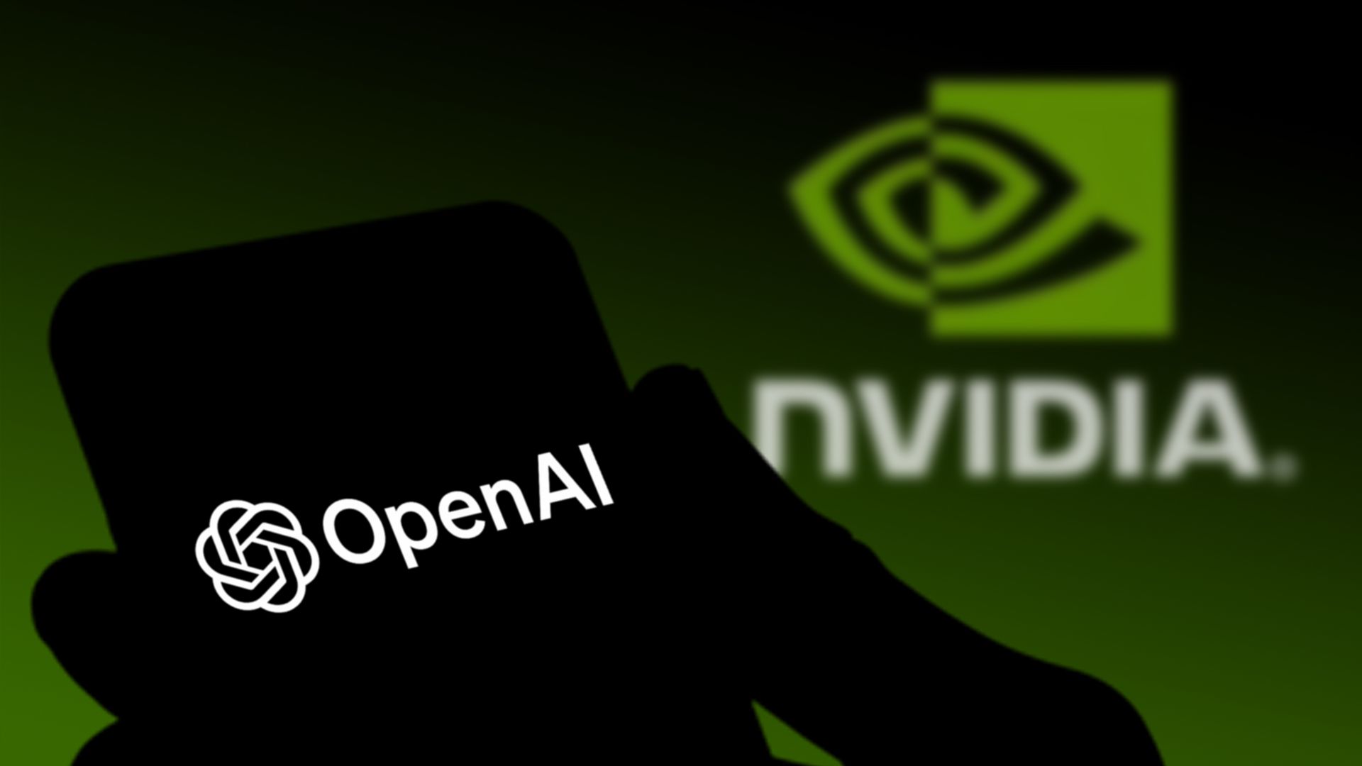Silhouette of a hand holding a phone displaying the OpenAI logo in white, with a blurred green NVIDIA logo in the background.
