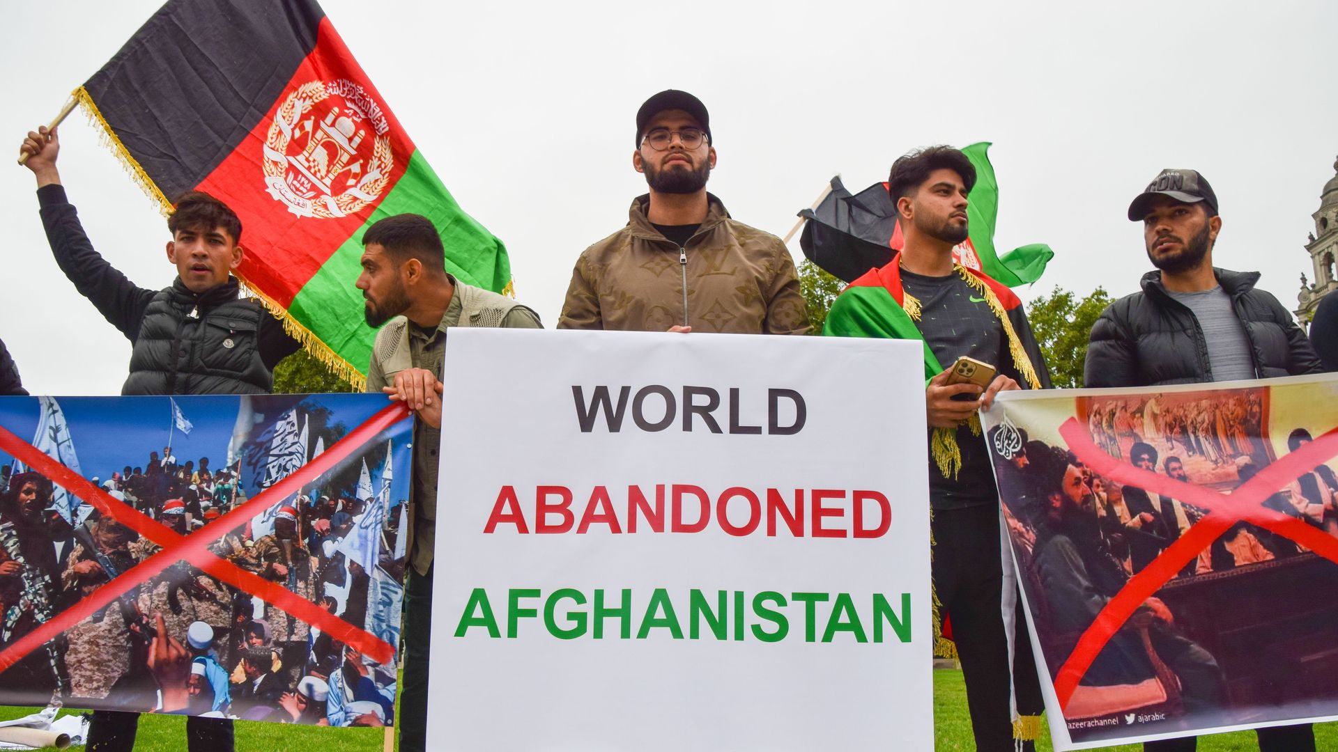 Photo of a protester holding a sign that says "World abandoned Afghanistan"