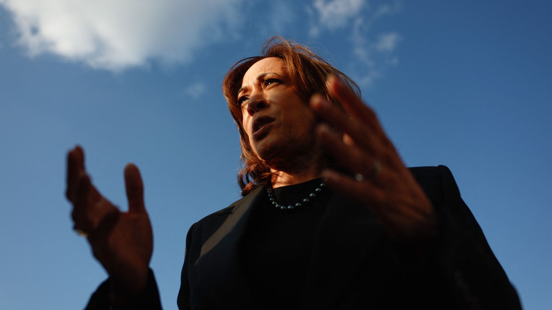 A photo of Kamala Harris from below with the sky in the background