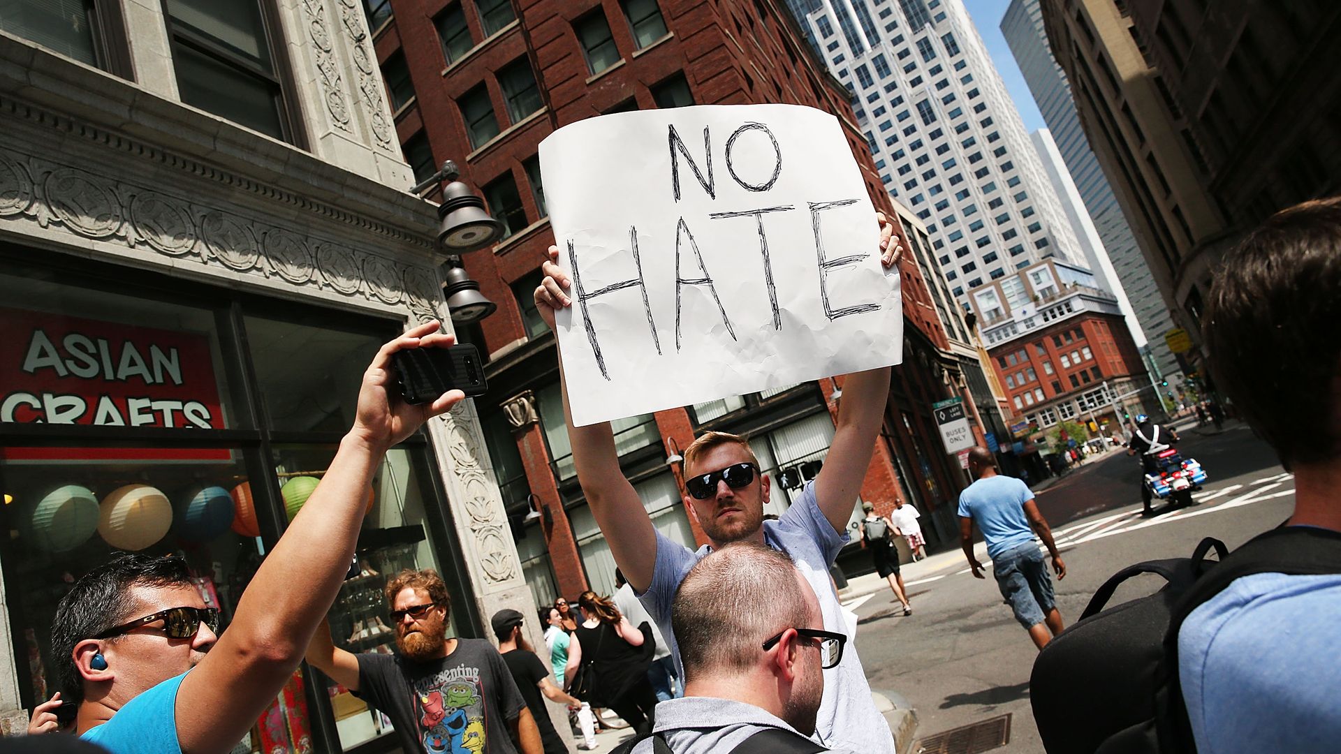 A counter-protestor in Boston holds a sign that reads "No hate" 
