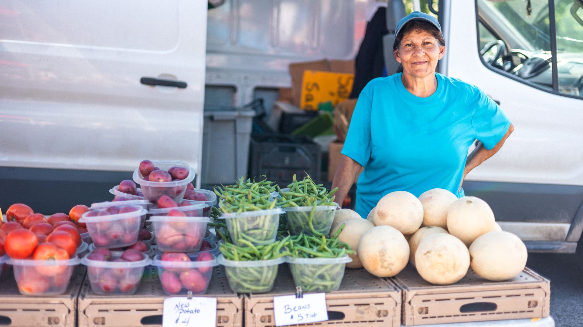 Photo shows a farmer with produce for sale on a table