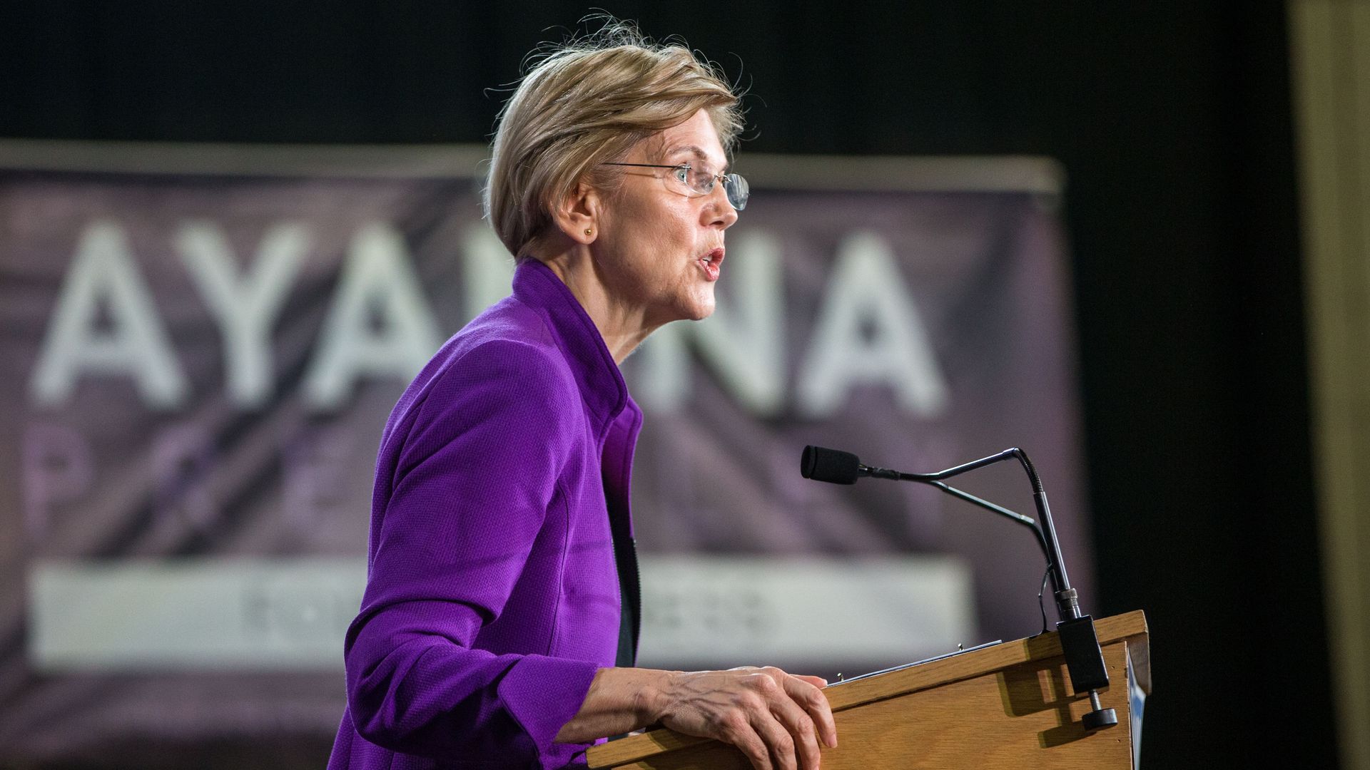 Elizabeth Warren stands at a podium on stage.