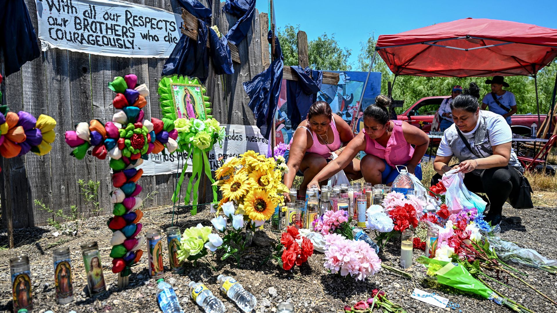 People place flowers and candles at a makeshift memorial where a tractor-trailer was discovered with migrants inside, outside San Antonio, Texas, on June 29, 2022.