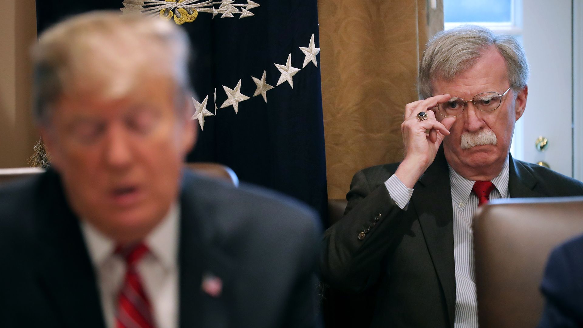National Security Advisor John Bolton (R) listens to U.S. President Donald Trump talk to reporters during a meeting of his cabinet in the Cabinet Room at the White House February 12, 2019.