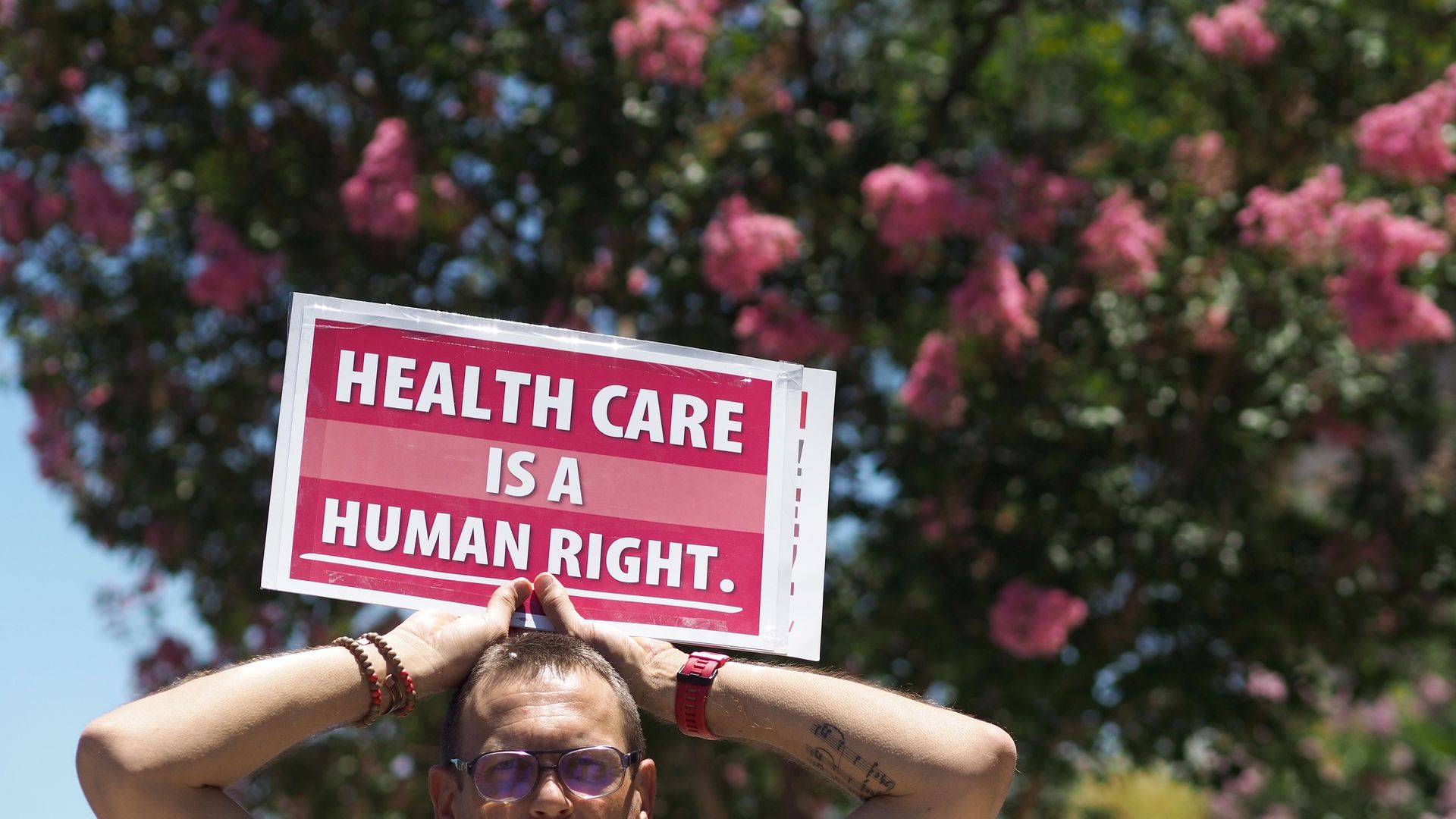 Picture of a person holding a sign that says "Health care is a human right"