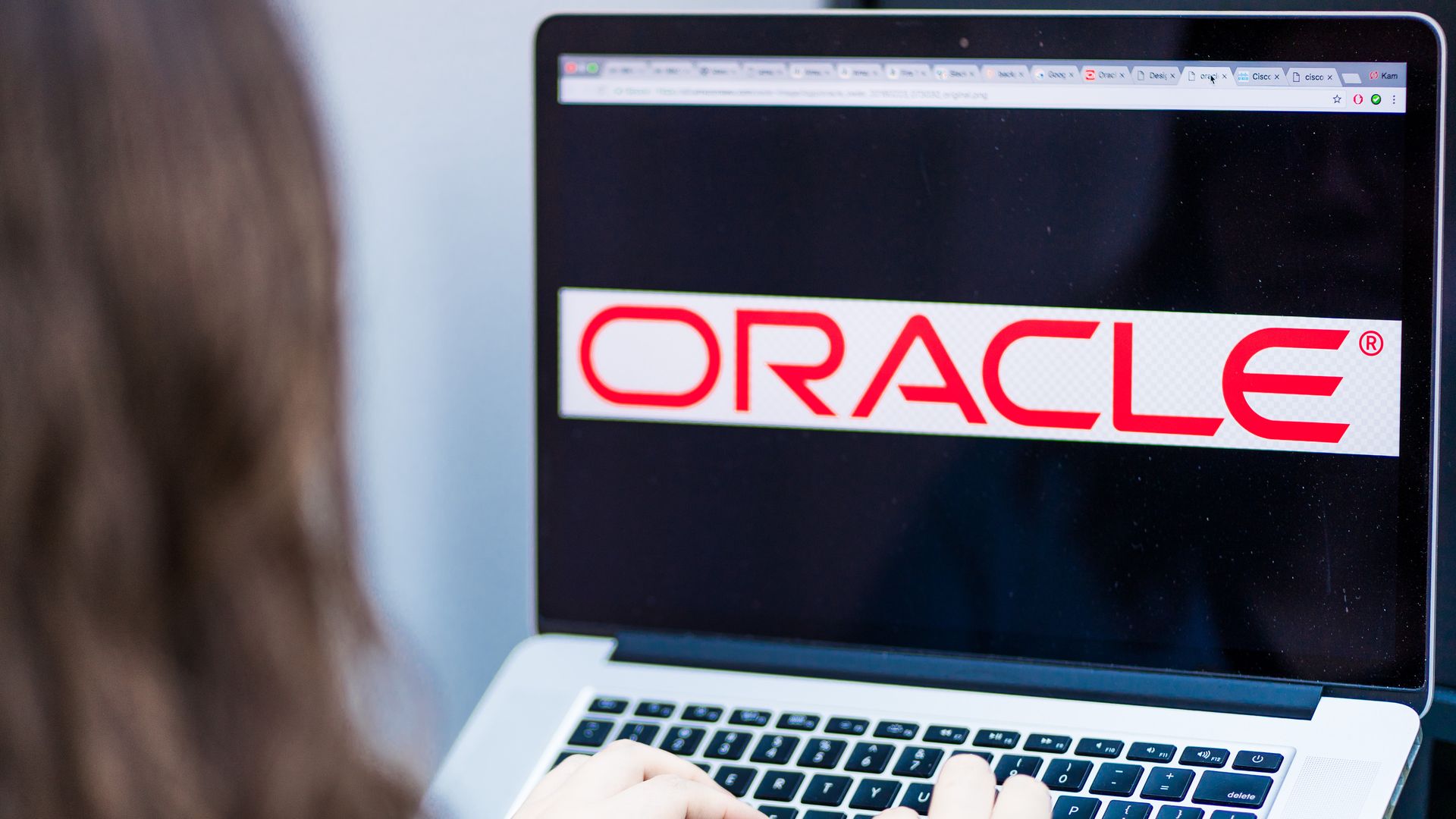 A woman uses a laptop computer displaying the Oracle logo