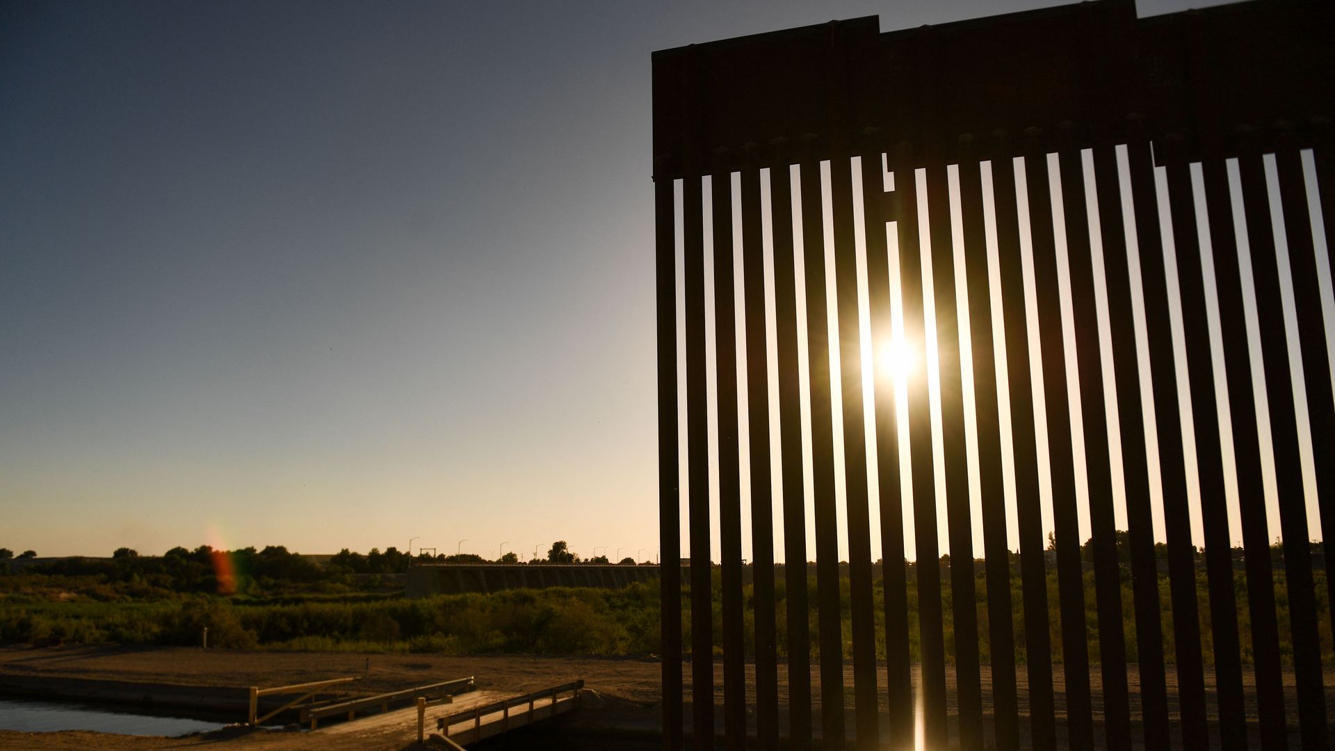 The sun sets along a gap in the border wall between the US and Mexico in Yuma, Arizona