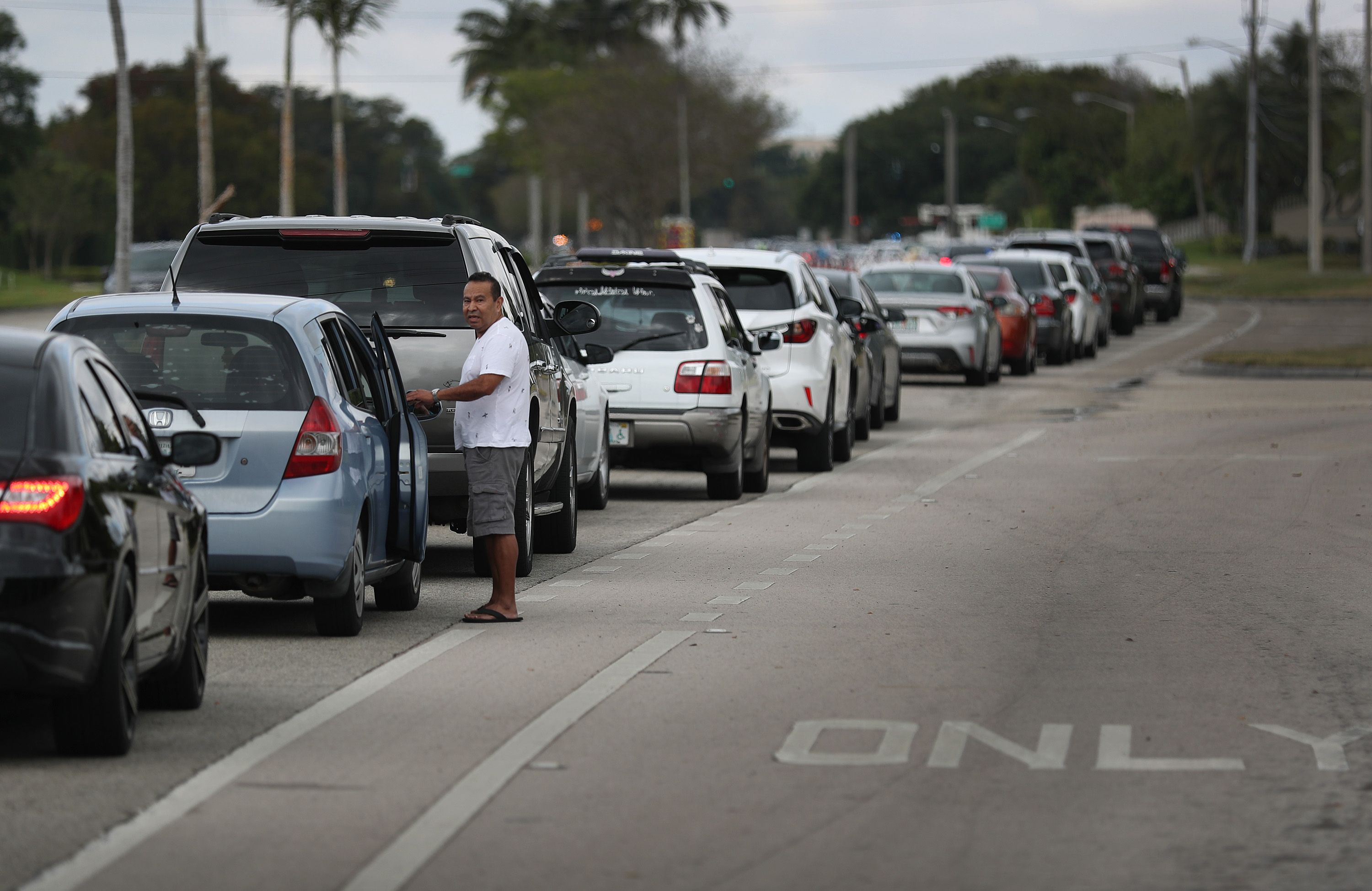 Jose Martinez waits in line next to his car to receive groceries provided by the food bank Feeding South Florida and distributed by the City of Sunrise on April 06