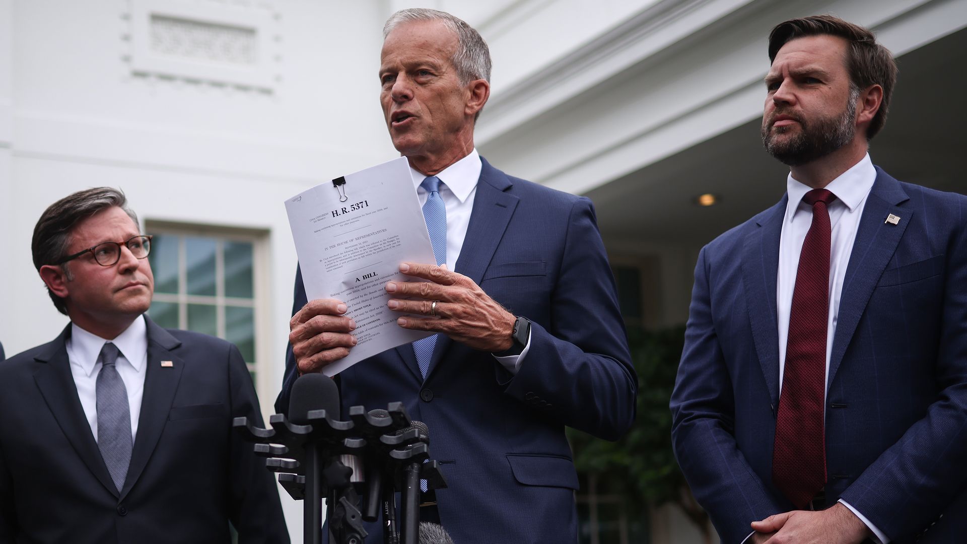 Senate Majority Leader John Thune holds a copy of a funding bill while speaking outside the White House with Speaker Mike Johnson (left) and Vice President Vance.