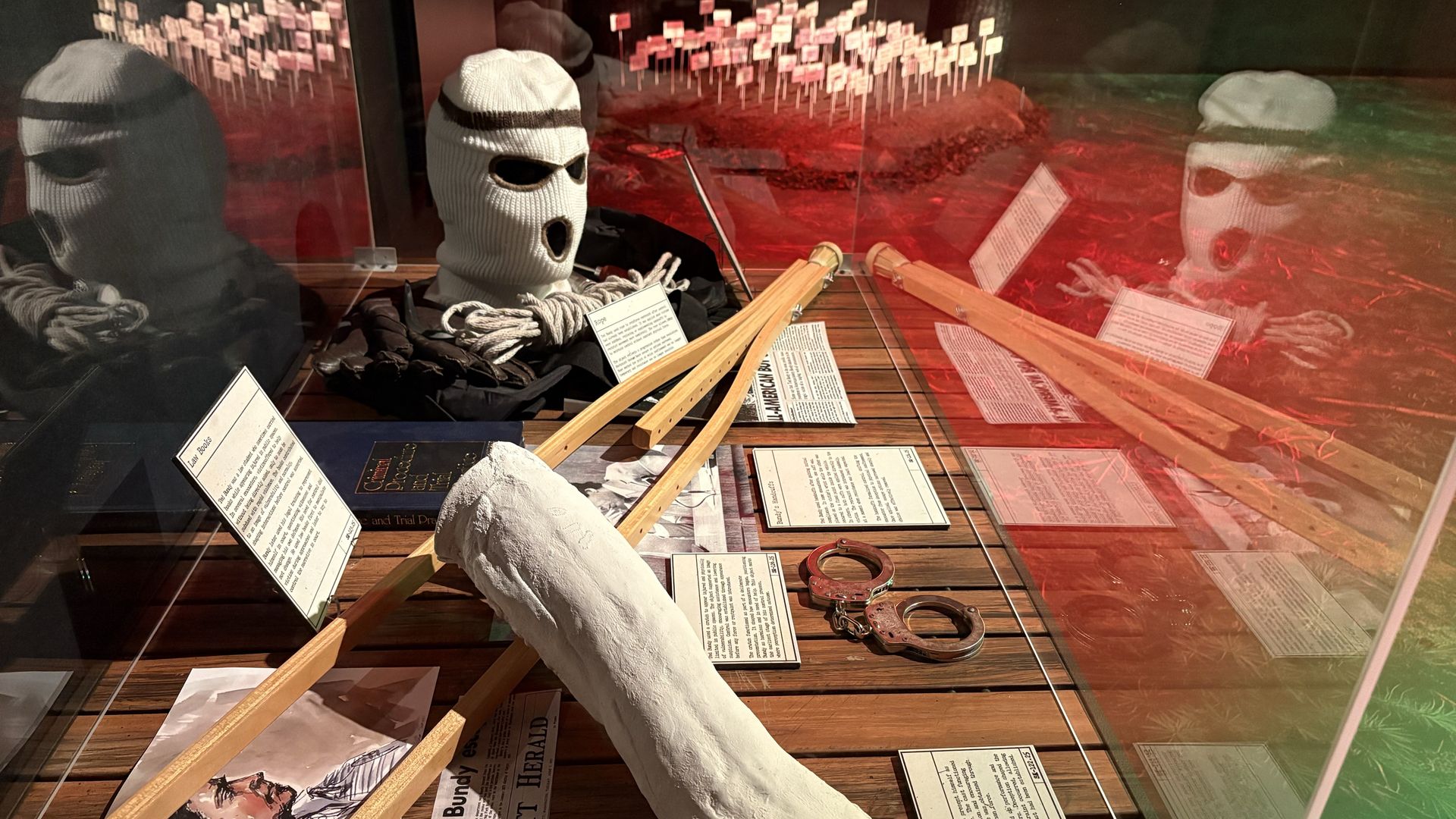 Ted Bundy's props: Crutches, cast, mask, handcuffs in a display case.