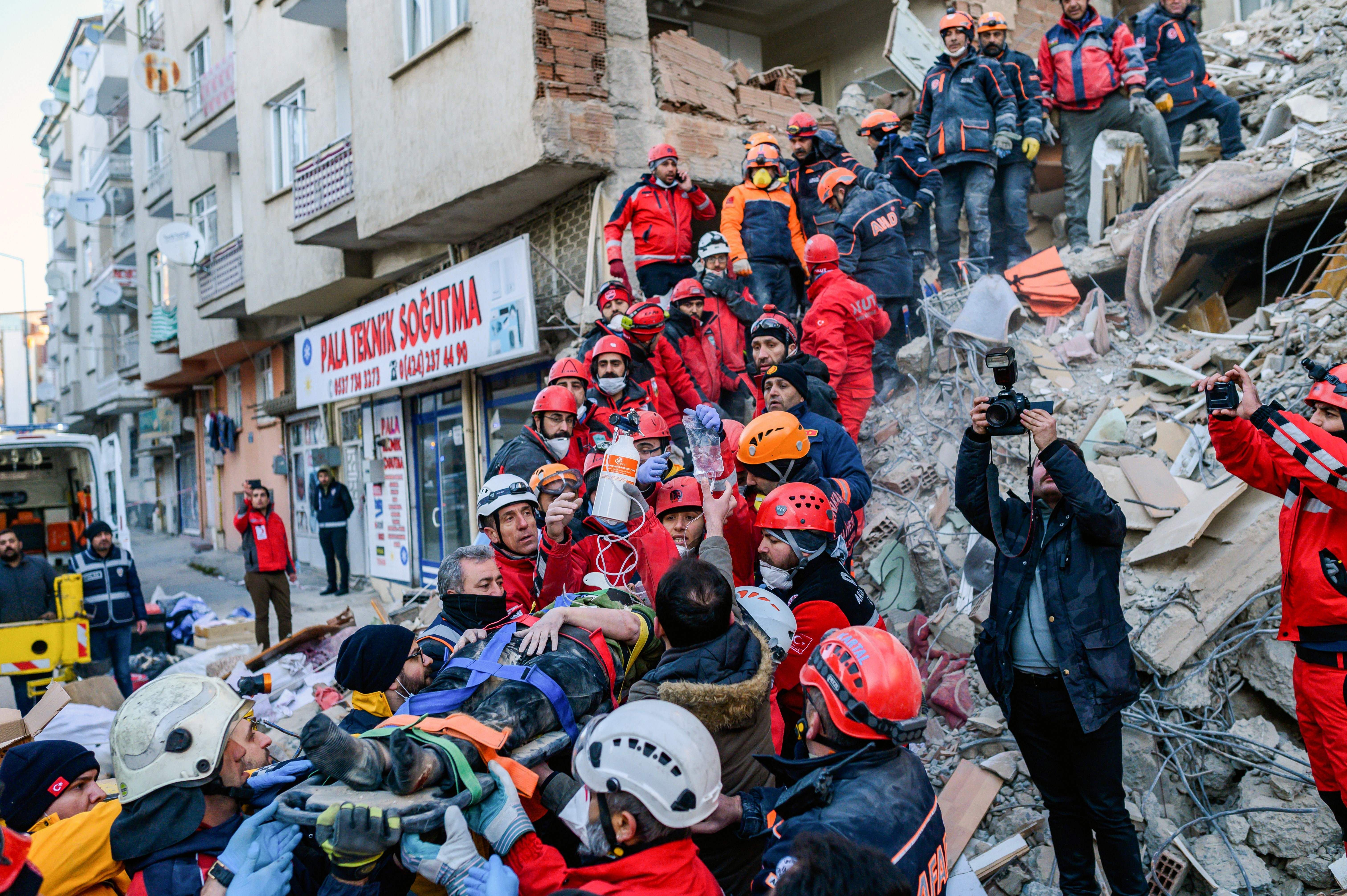 Rescue workers evacuate an injured woman from the rubble of a building after an earthquake in Elazig