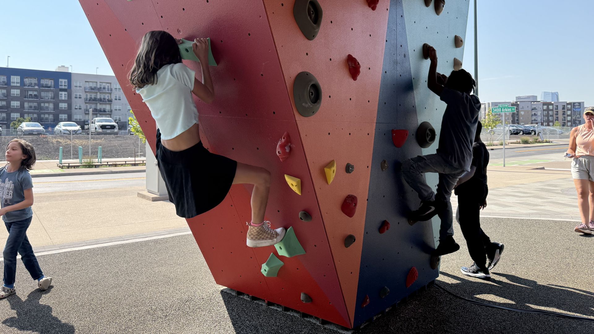 Children climbing a colorful outdoor rock climbing wall.