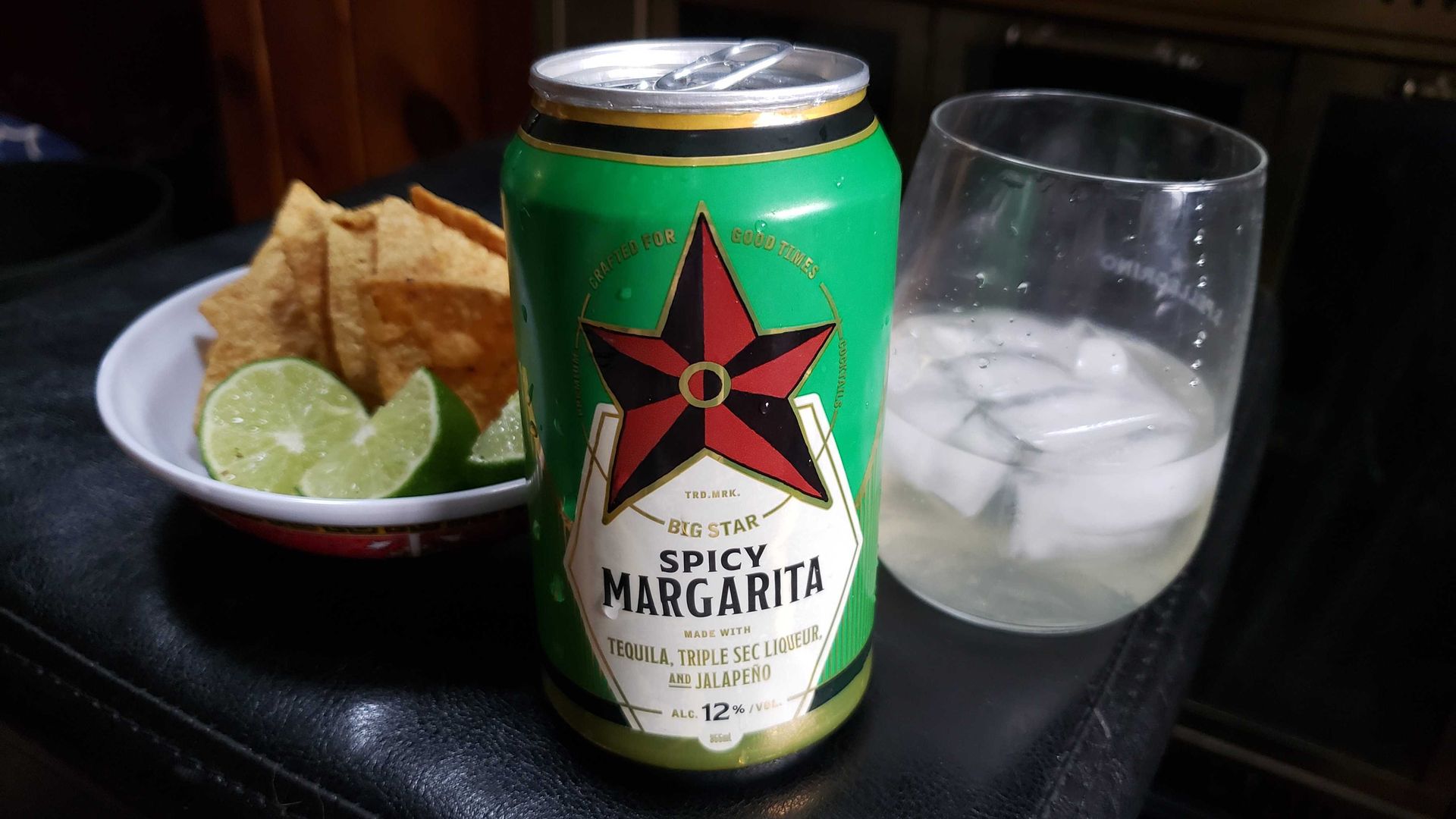 Photo of a canned cocktail next to a cocktail glass and tortilla chips on a plate. 