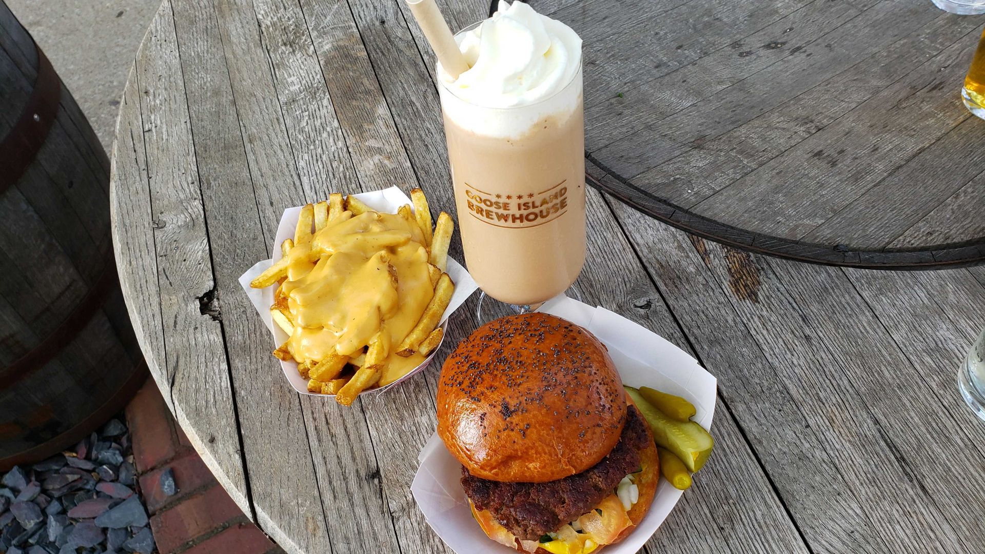 Photo of a hamburger, fries and a milkshake on a table.