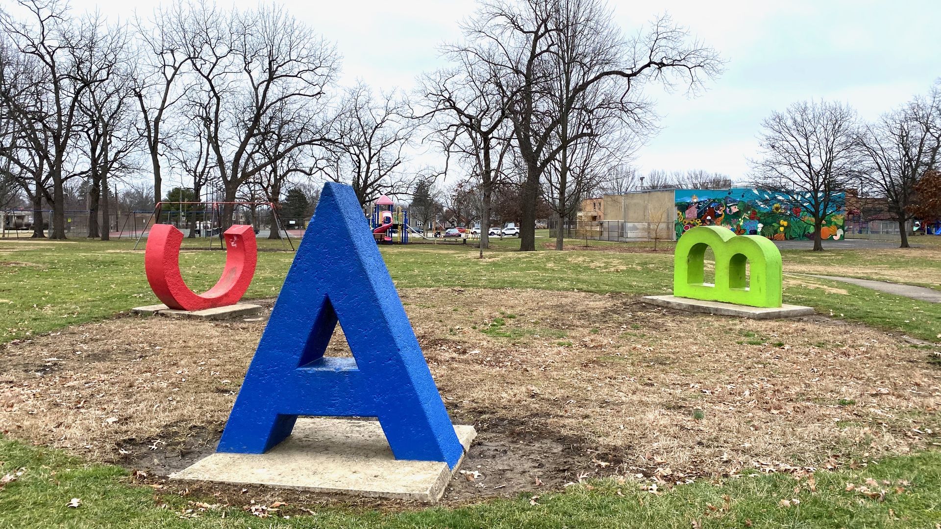 Large concrete sculptures of a blue "A" in the foreground and a red "C" and green "B" in the background on their sides