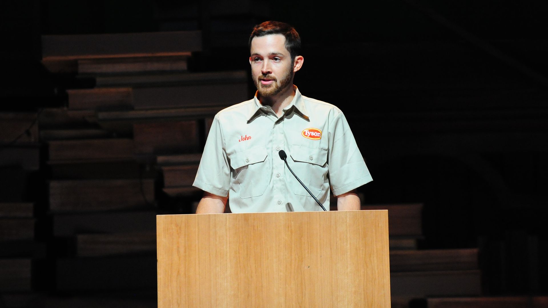 A photo of John R. Tyson, CFO of Tyson Foods, speaking from a podium in 2021, wearing khakis.