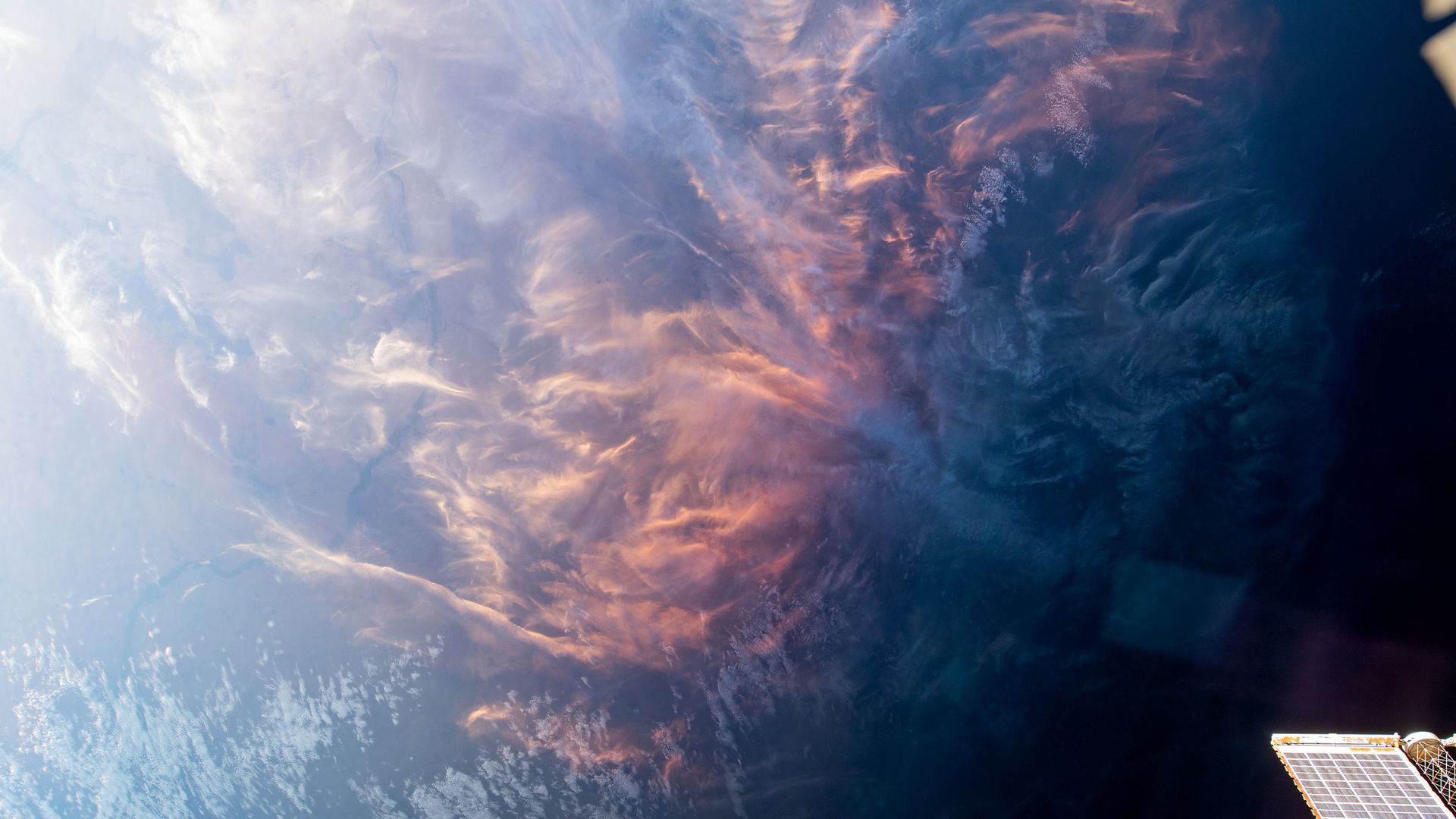 Pink, wispy clouds above Earth as seen from the International Space Station