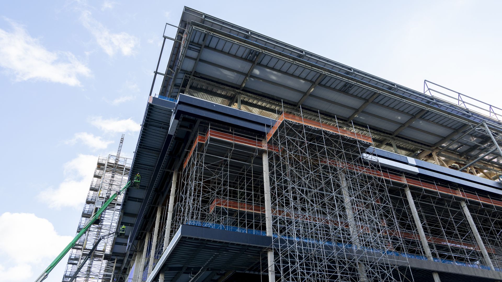 Construction on the new Tennessee Titans stadium is seen, with scaffolding and cranes surrounding the metal frame.