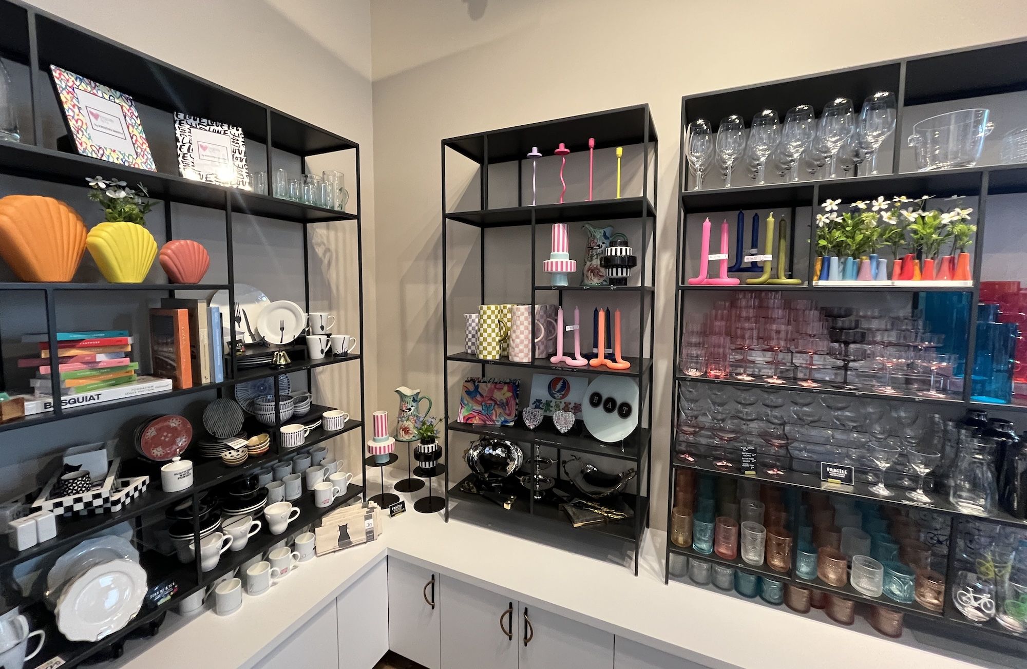 Shelves with brightly-colored vases, candle holders, dishes and glasses.