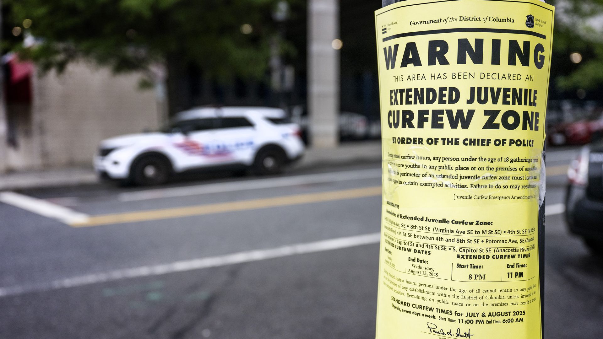 A placard on a street lamppost warns of an extended juvenile curfew zone