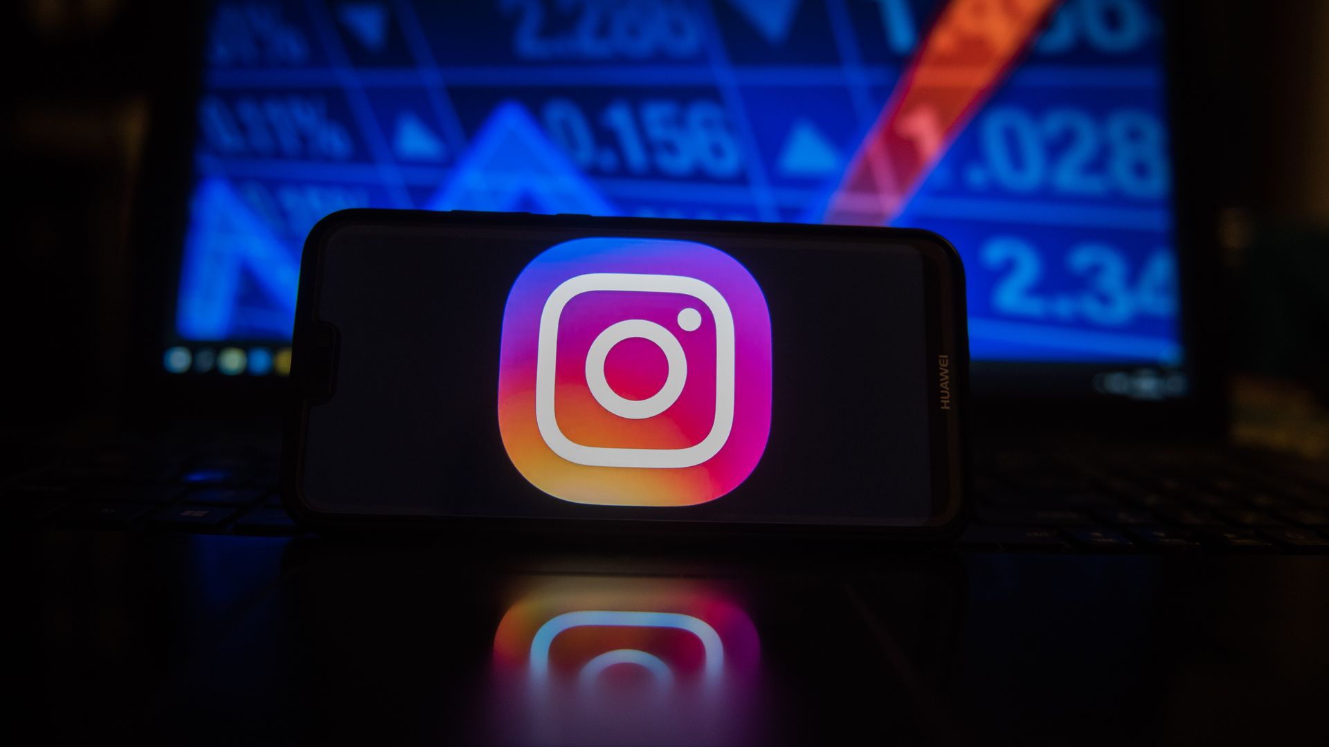 Instagram logo on a phone in dark room.