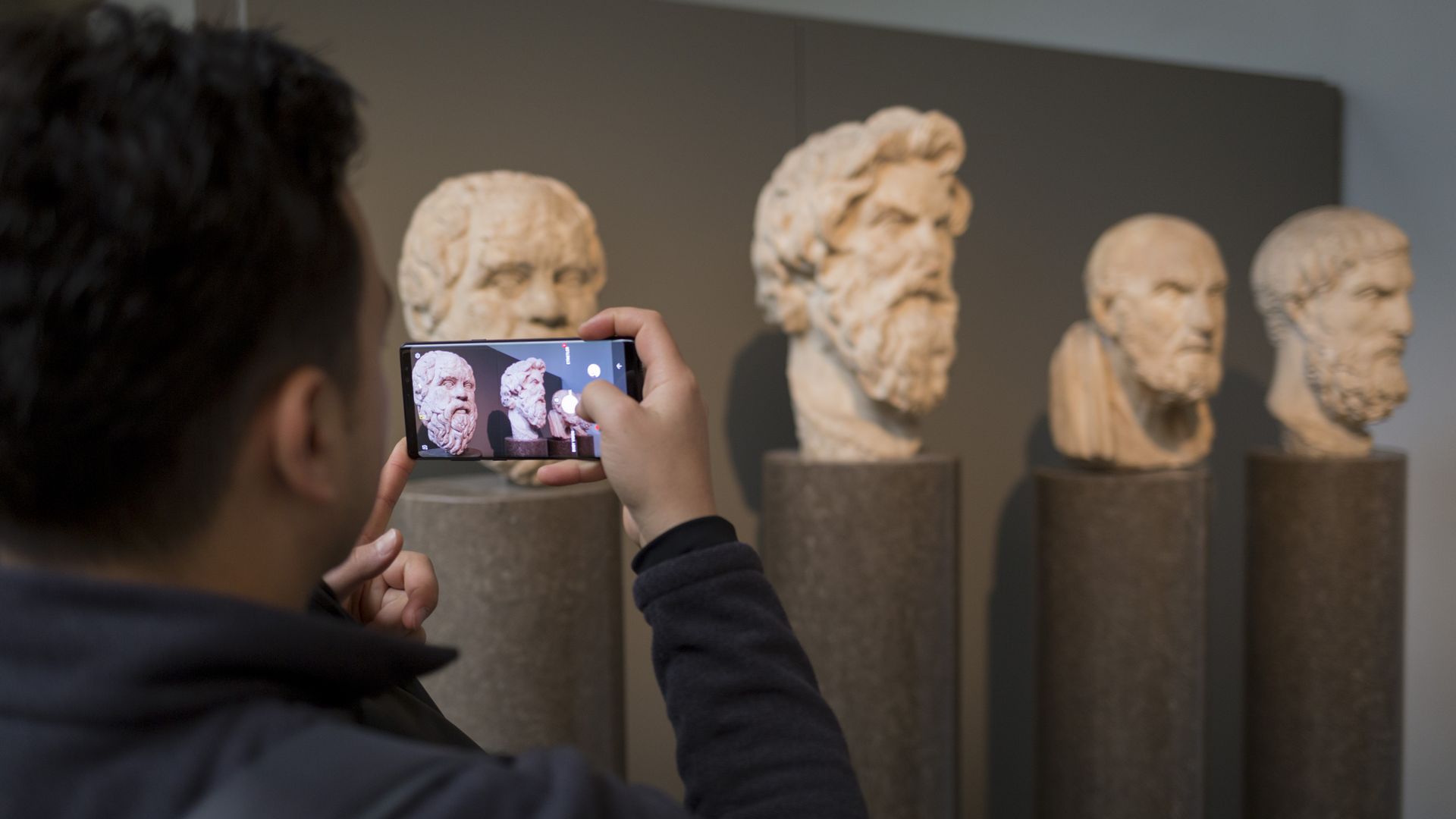 A visitor to the British museum takes a photo on his smartphone. 