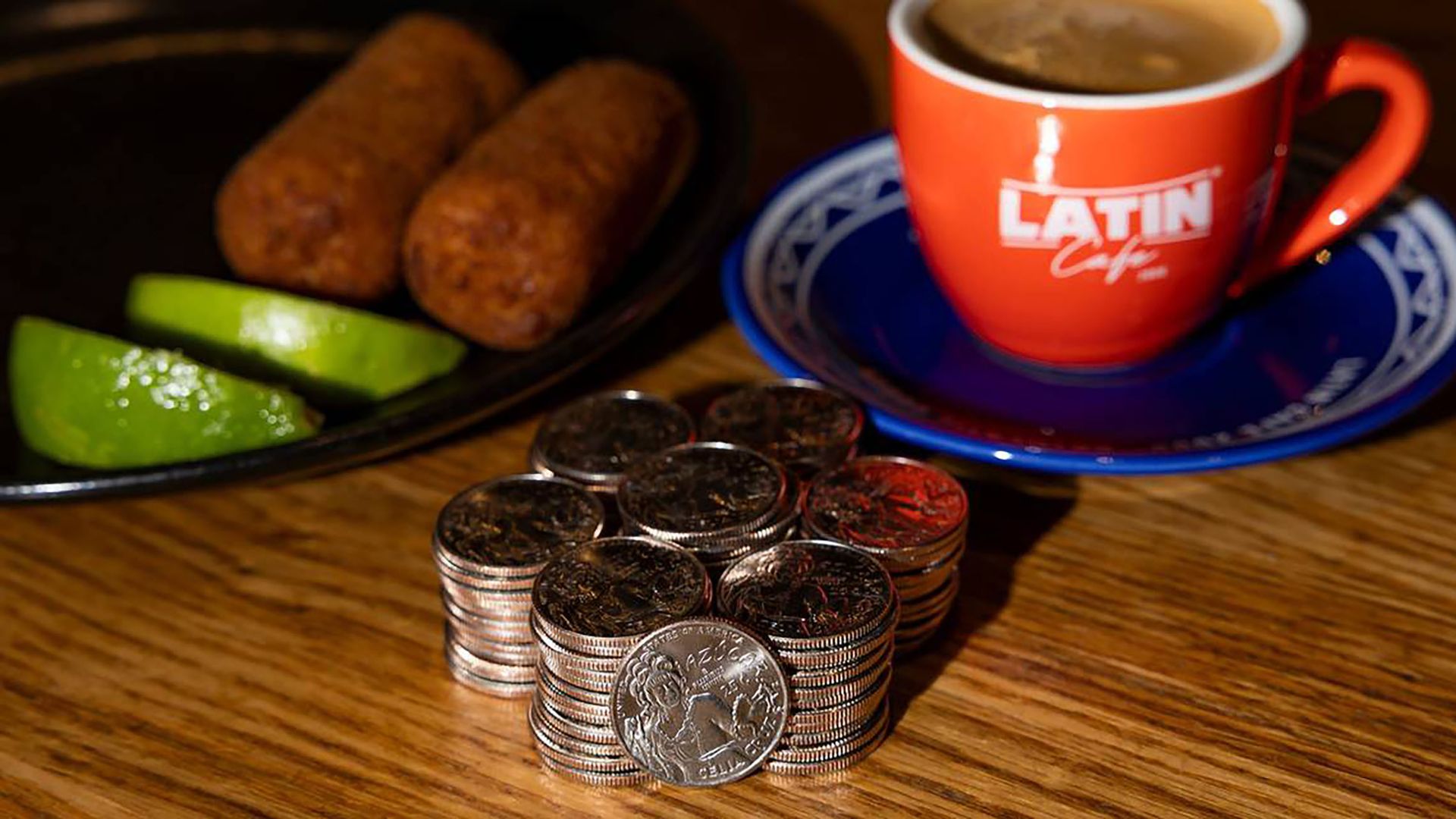 A stack of quarters with croquetas and coffee in the background. 