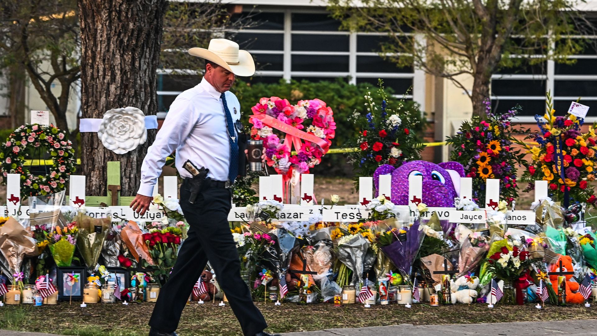 A police officer walking past a memorial outside Robb Elementary School in Uvalde, Texas, on May 27.