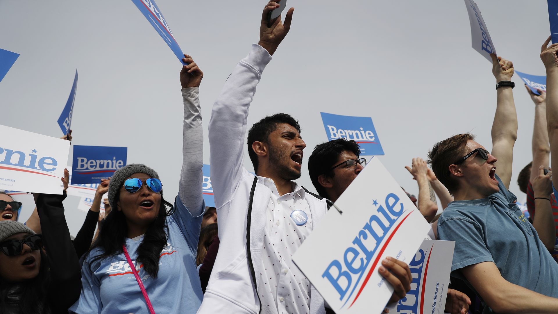 Young people hold signs for Bernie Sanders at rally