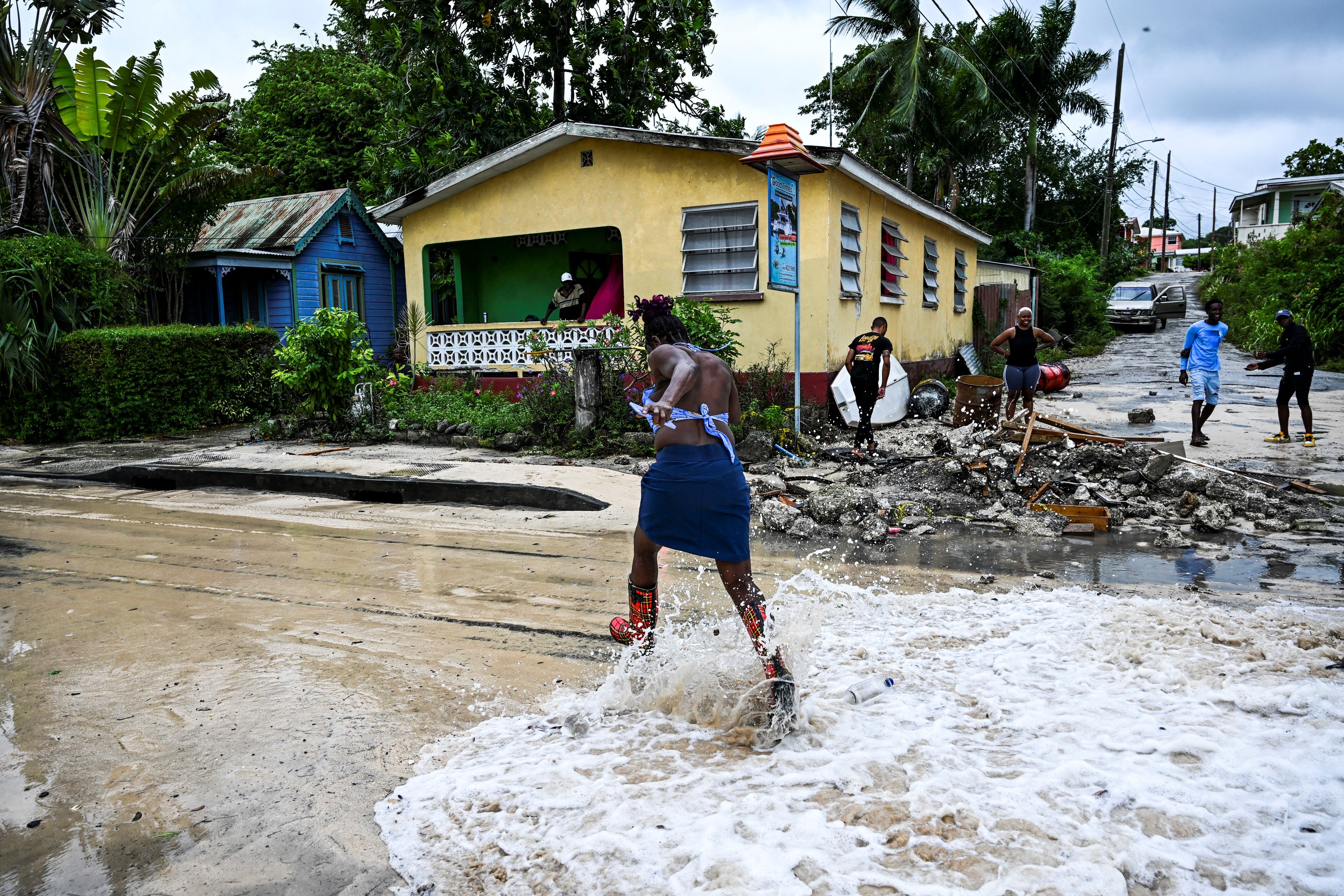 A woman runs as water from the sea floods a street after the passage of Hurricane Beryl in the parish of Saint James, Barbados, near Bridgetown on July 1, 2024. Officials in Barbados said the island was buffeted by high winds and pelting rain, but appeared to have avoided disaster, reporting no inju