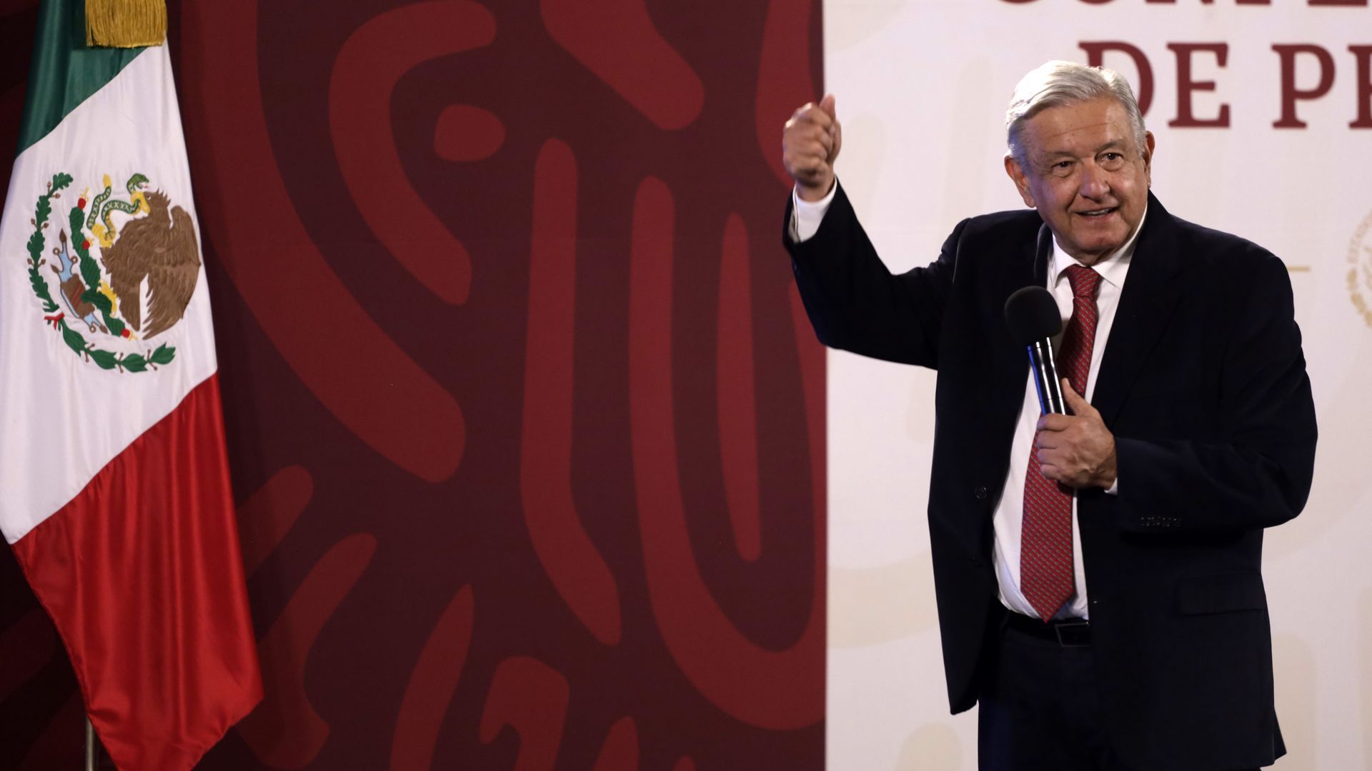 Mexican President Andrés Manuel López Obrador raises his hand and uses the other to hold a microphone while he speaks at a news briefing