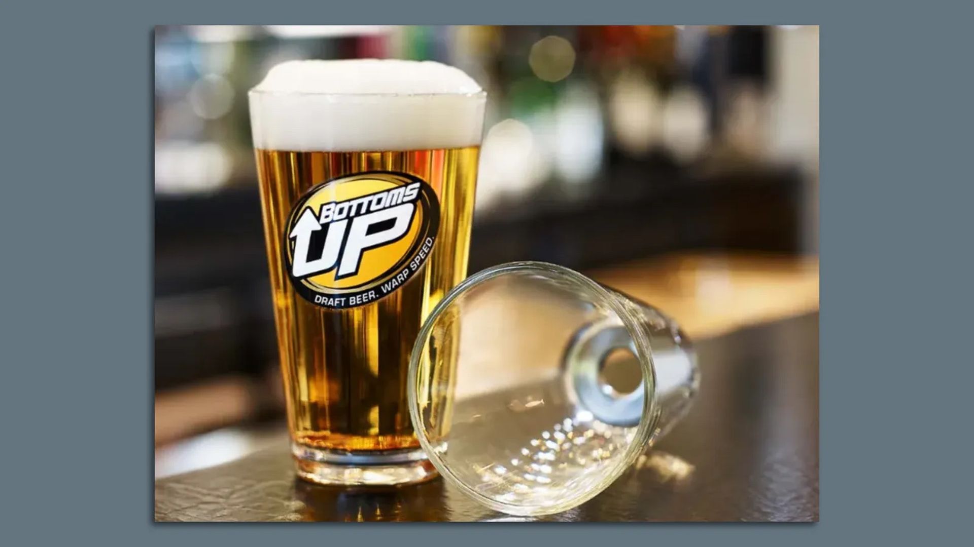 A glass full of beer and an empty one on a bar