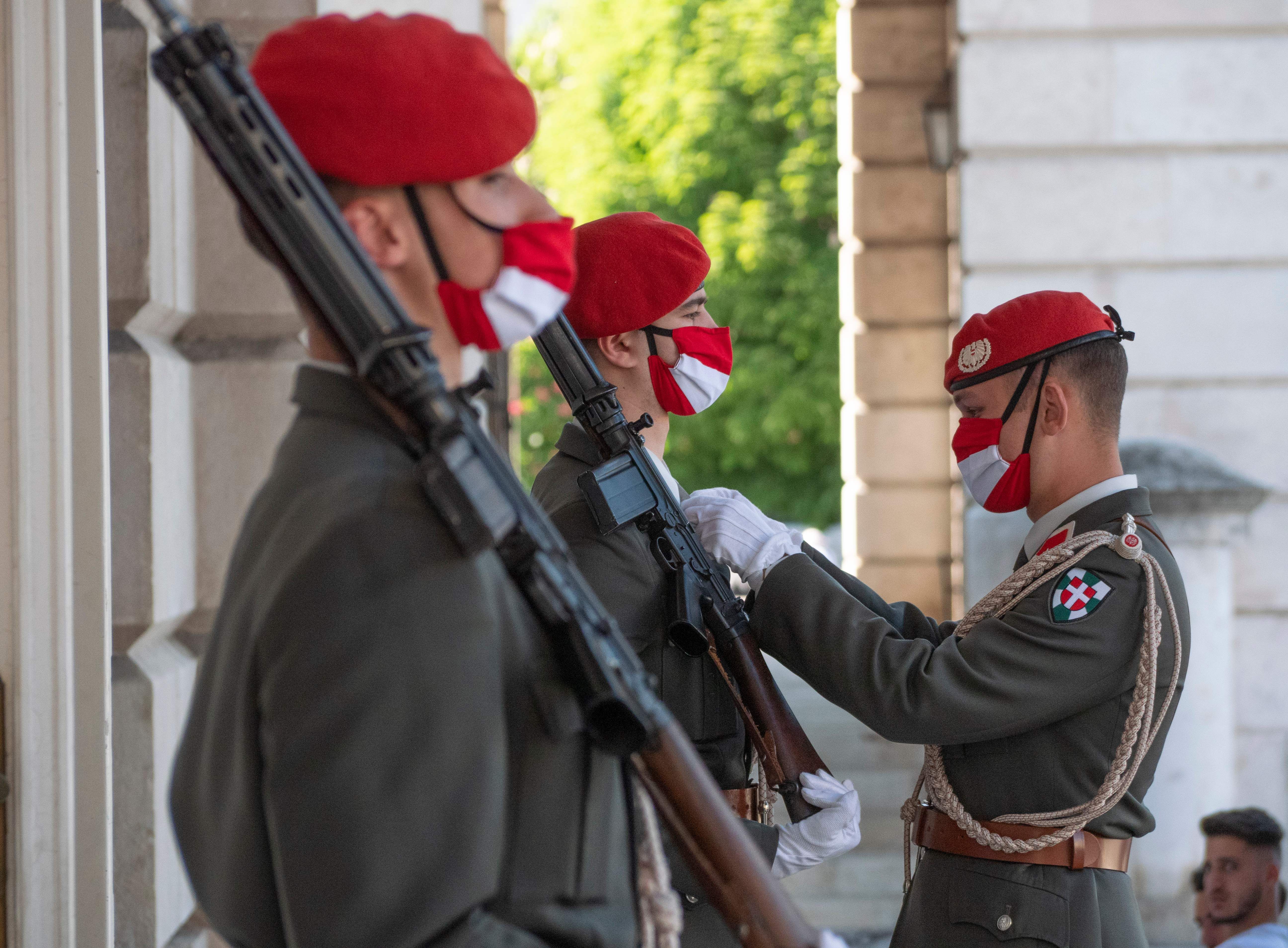 An Austrian officer checks the outfit of a soldier while he stands guard outside the 'Weiherraum' memorial on May 8, 2020, in Vienna.
