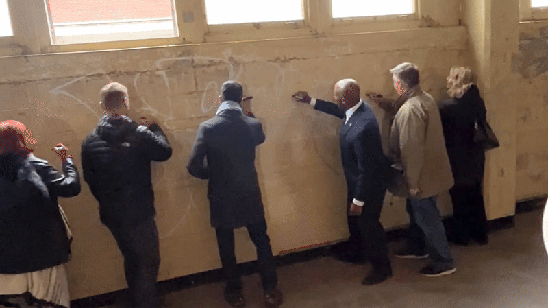 Gif shows city leaders signing their name on a wall at the Hardesty complex