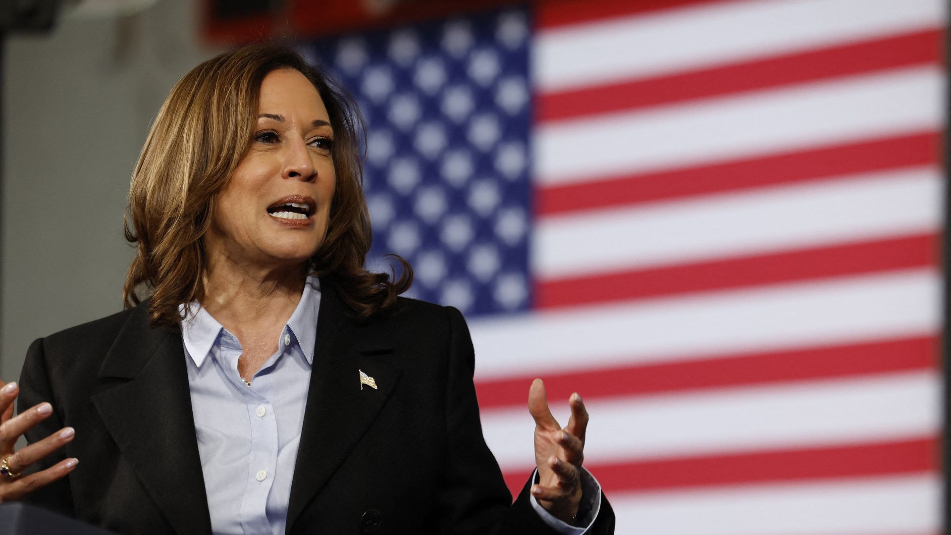 Vice President Kamala Harris speaks at a Labor Day event in front of an American flag.